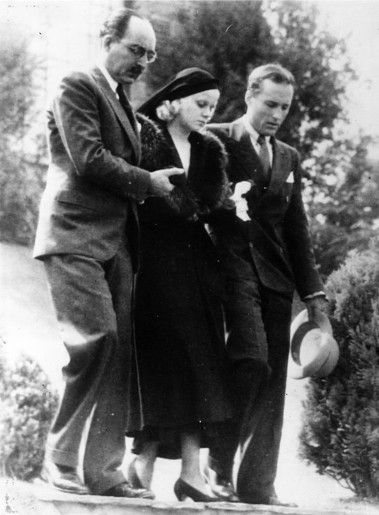 American film actress Jean Harlow being assisted from her house by her step-father Mario Bello and a relative Donald Robertson on her way to the funeral of her husband Paul Bern, who was found shot dead at his Beverly Hills home. | Source: Getty Images