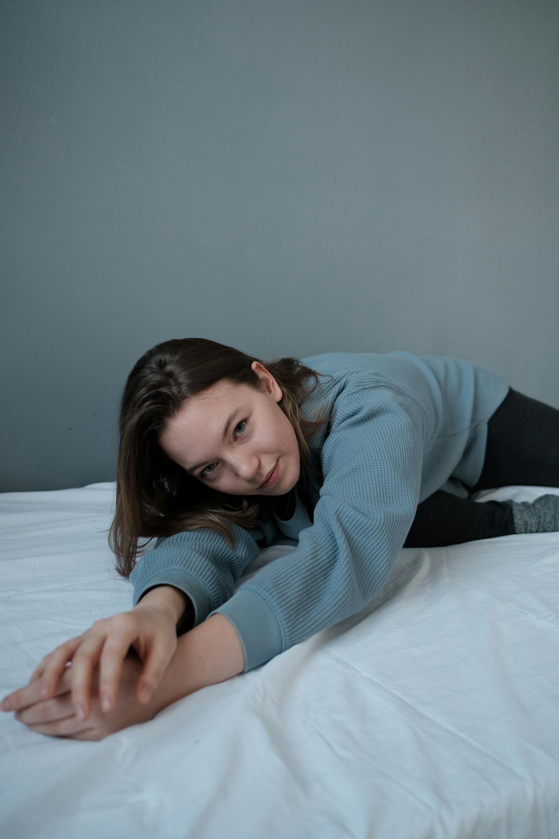 A teenage girl lying on an unmade bed | Source: Pexels