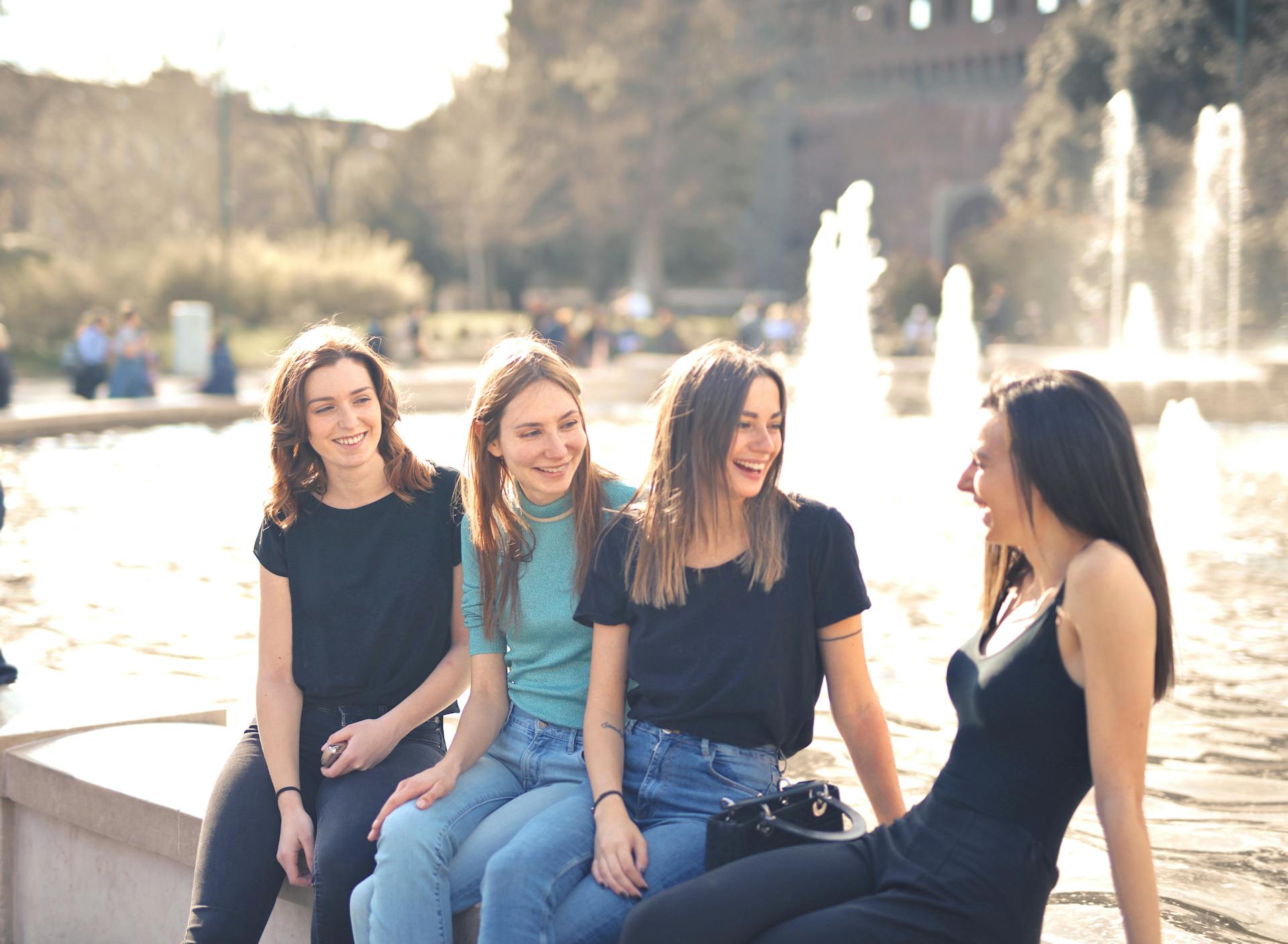 Women laughing while sitting near a fountain | Source: Pexels