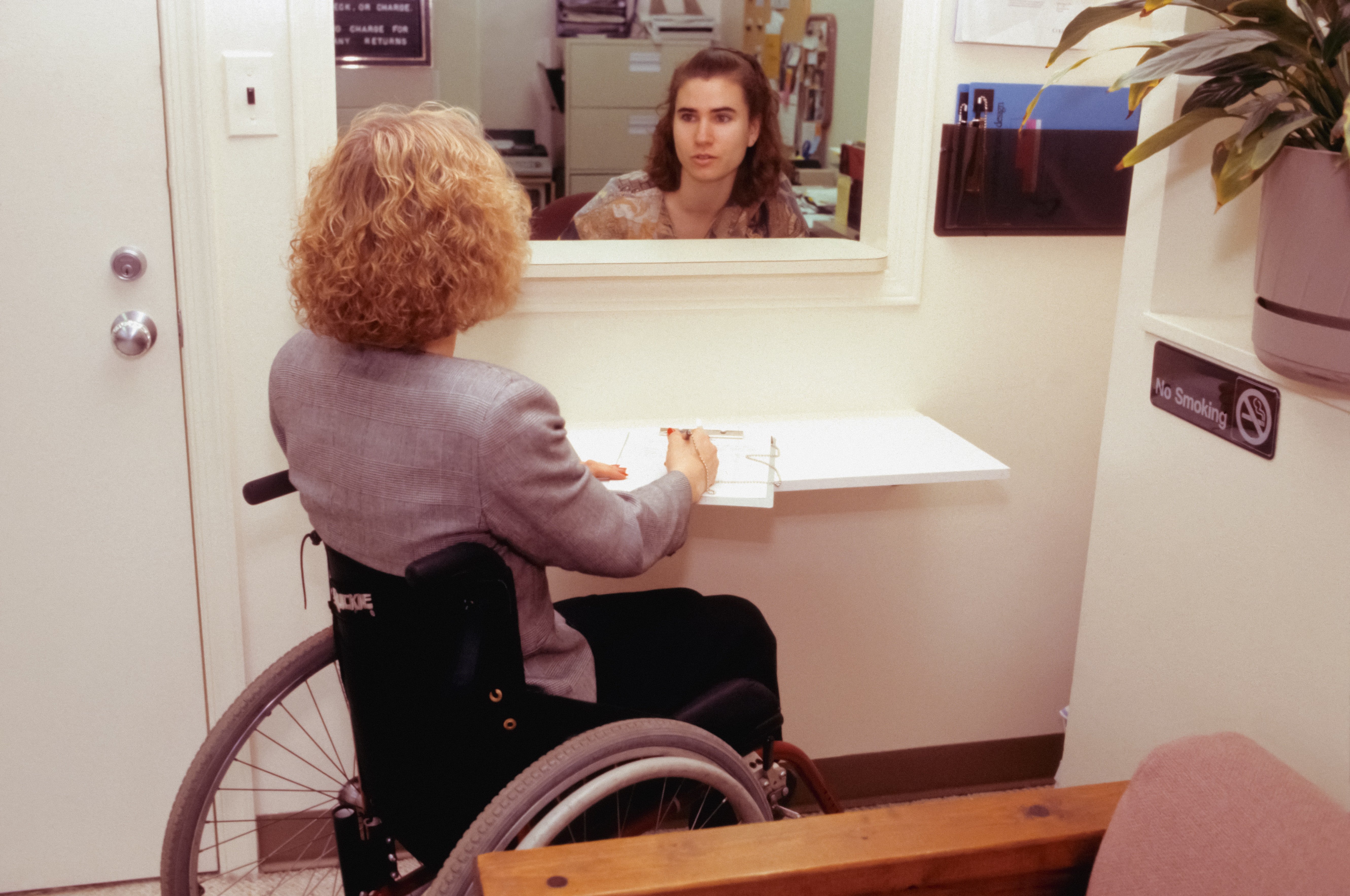 Mujer en silla de ruedas frente a una recepción. | Foto: Unsplash