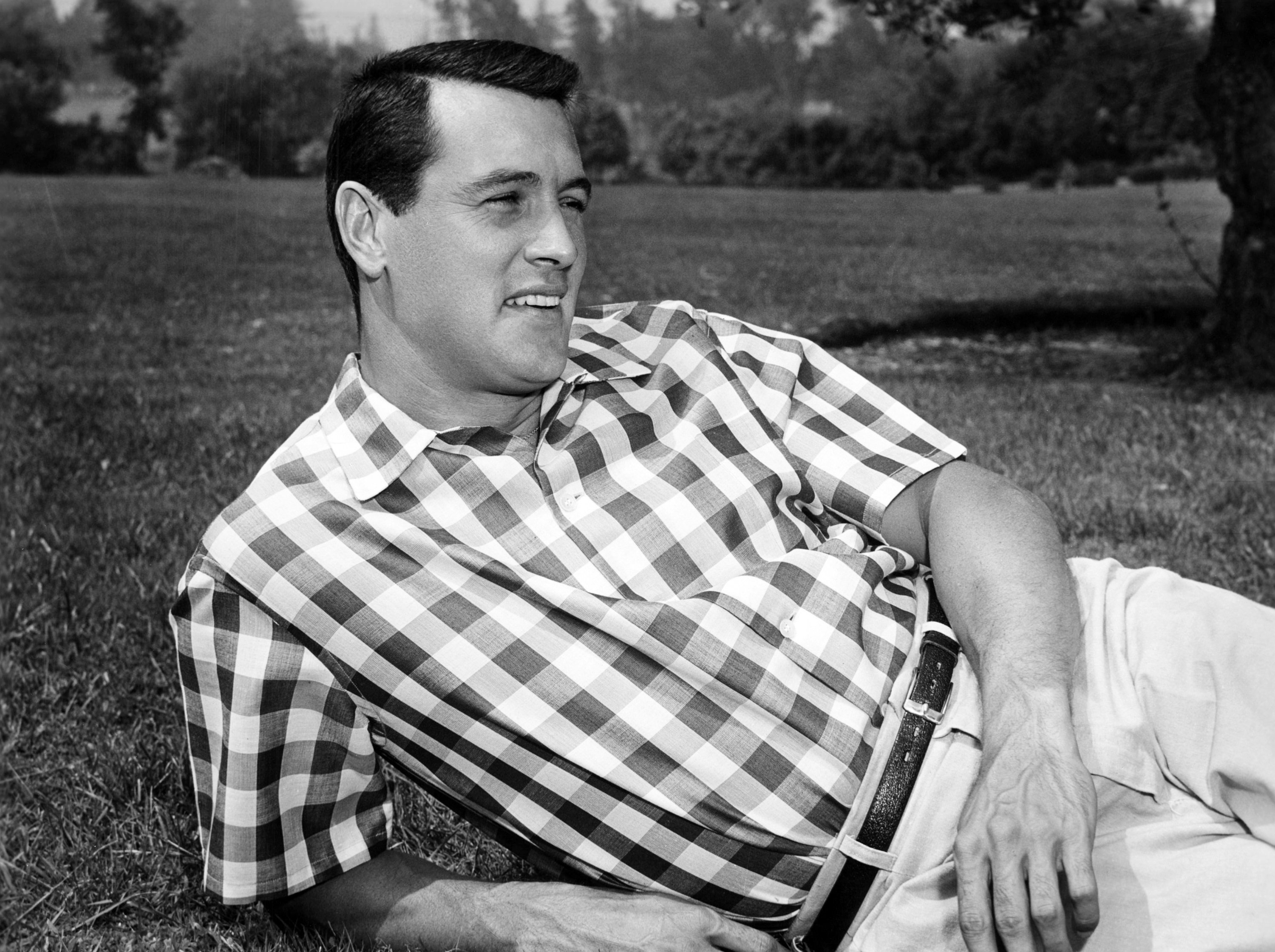 Rock Hudson posing for a picture while lying on the grass in 1955 | Source: Getty Images