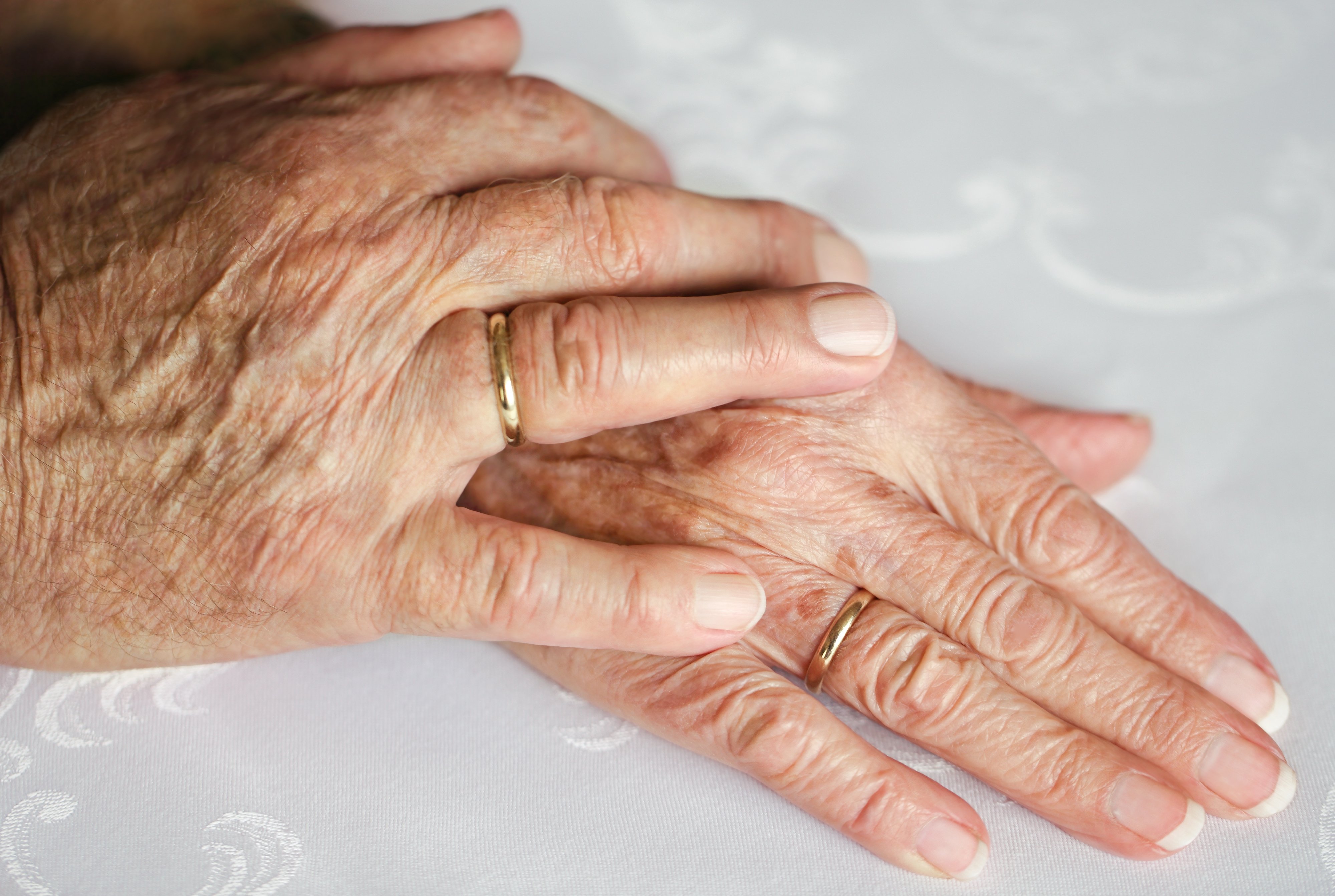An elderly couple's hands with golden wedding rings. | Source: Shutterstock