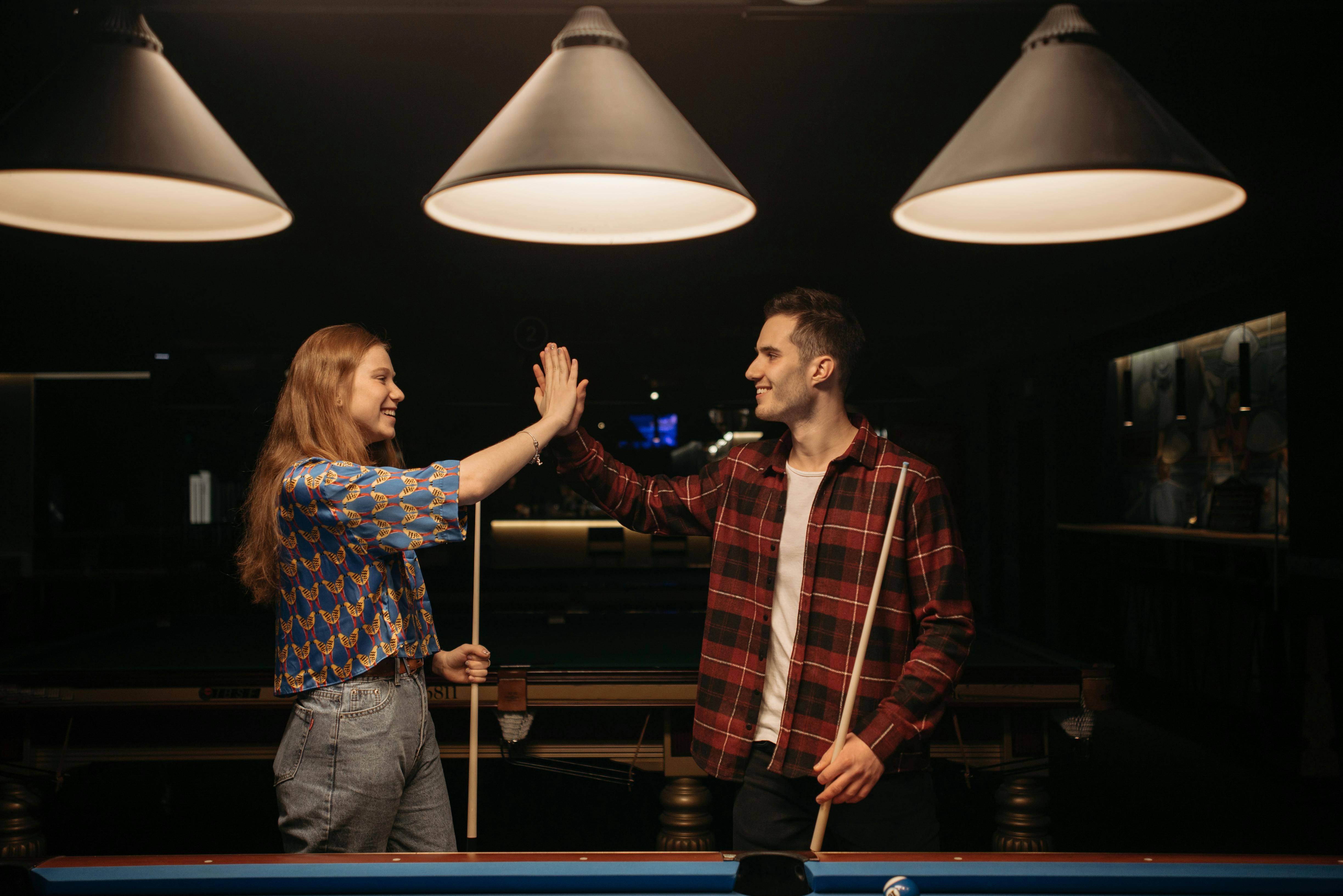 A man and woman high-fiving near a pool table | Source: Pexels
