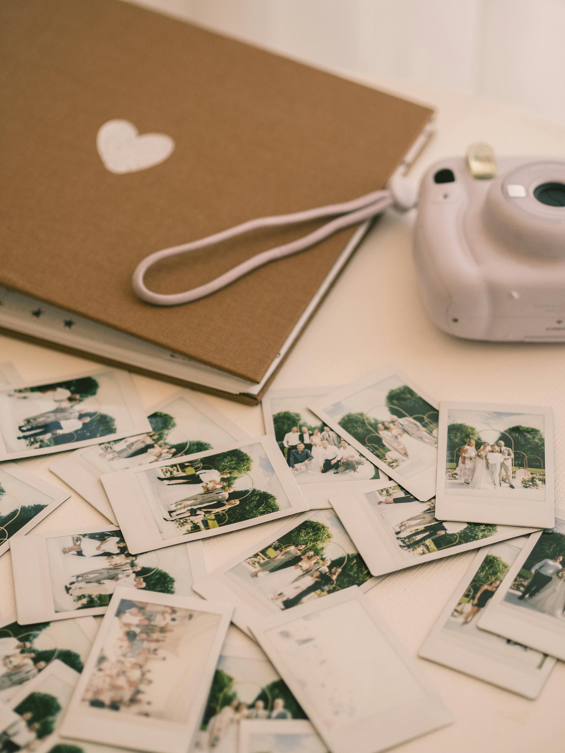 A photo album, wedding photos, and a camera lying on a white surface | Source: Pexels