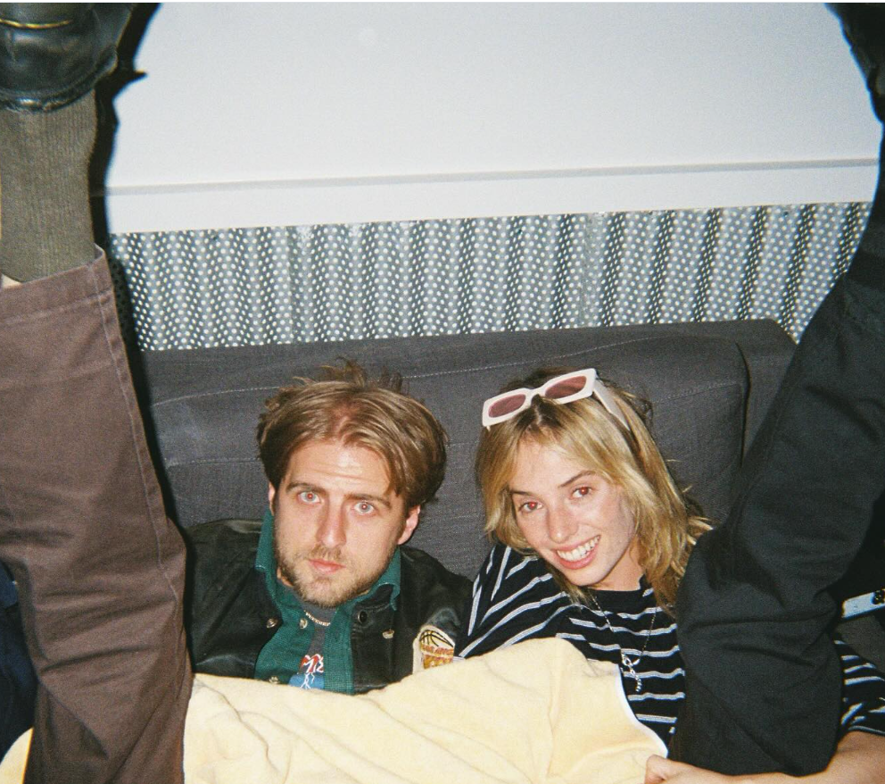 Maya Hawke smiles brightly in a striped top with white sunglasses perched on her head, while Christian Hutson looks calmly at the camera. | Source: Instagram/christianleehutson