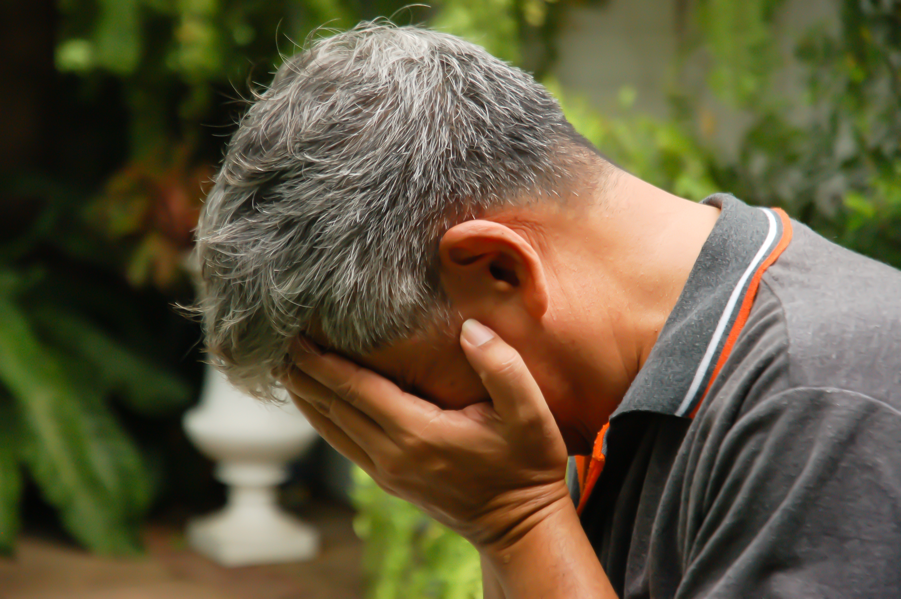 A depressed senior man covering his face with his hands | Source: Shutterstock