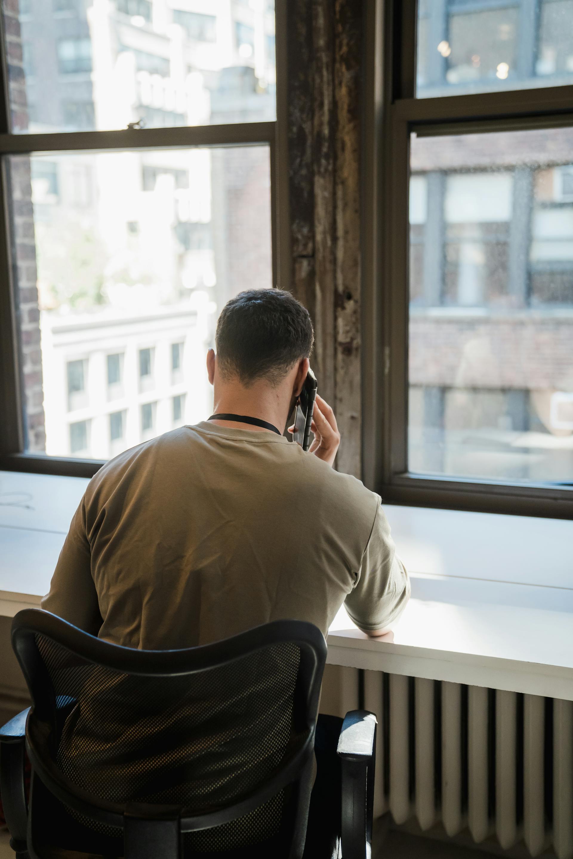 A man talking on his phone while sitting in the office | Source: Pexels