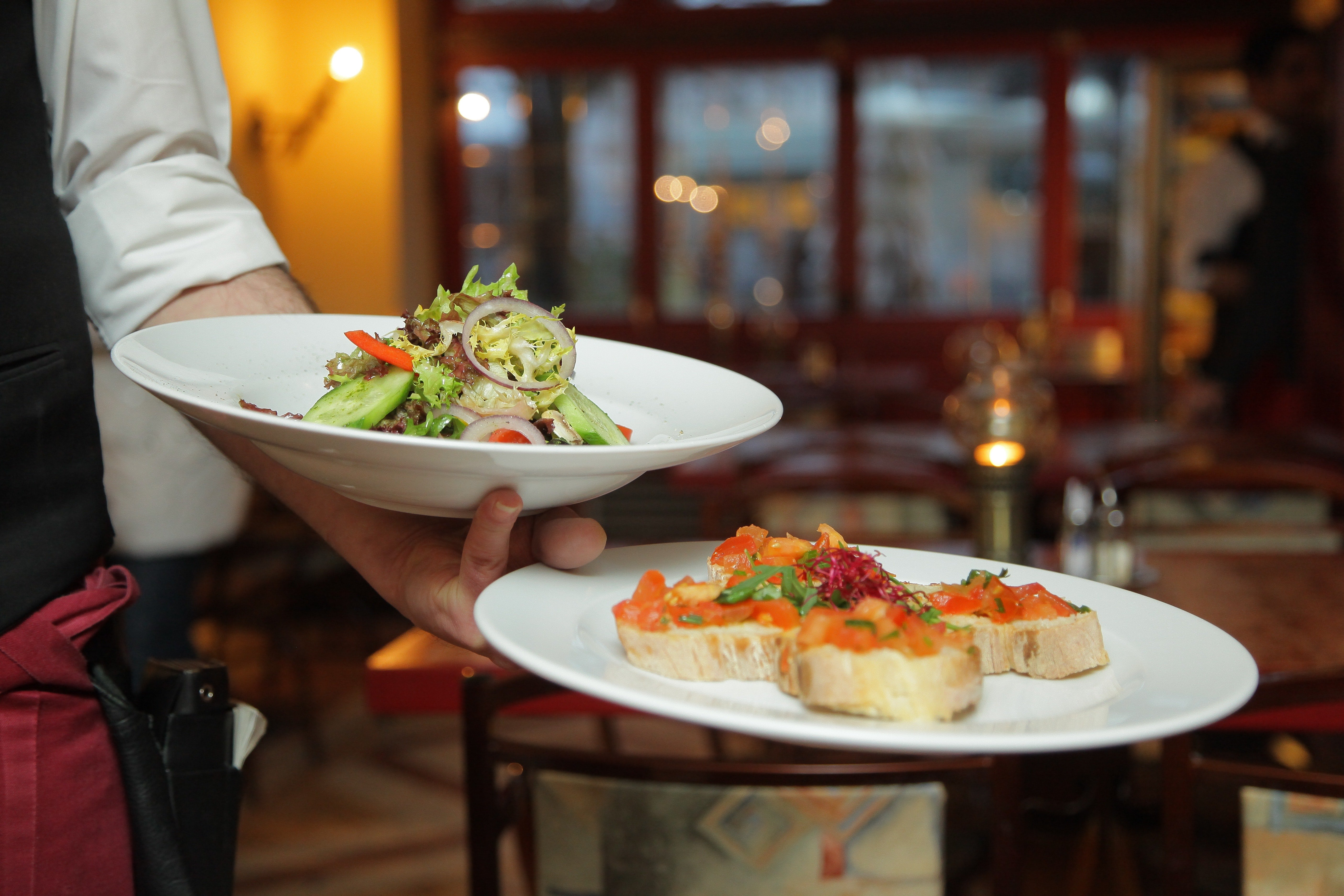 Mesero con platos de comida. | Foto: Pexels
