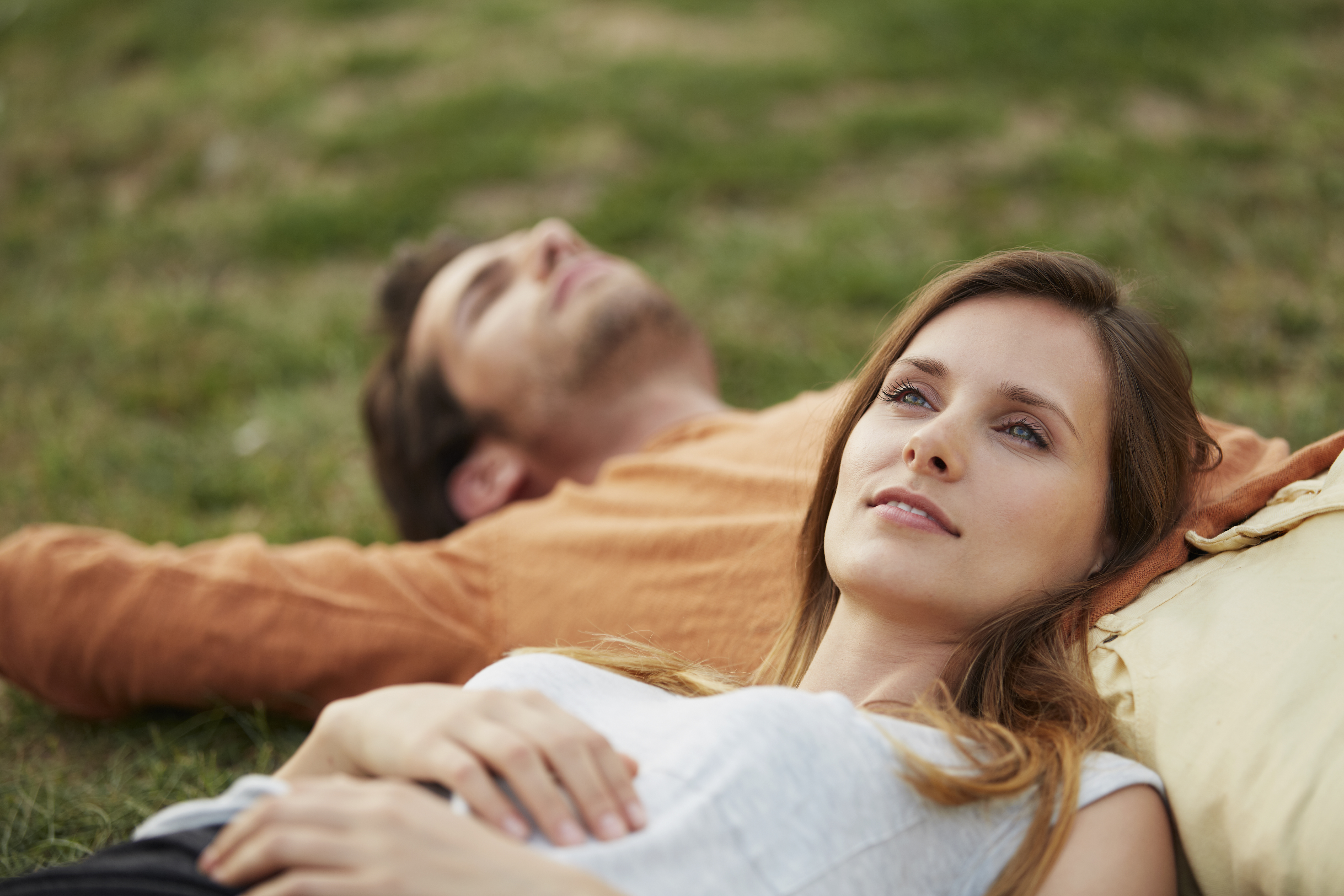 Woman resting head on man's stomach at park | Source: Getty Images