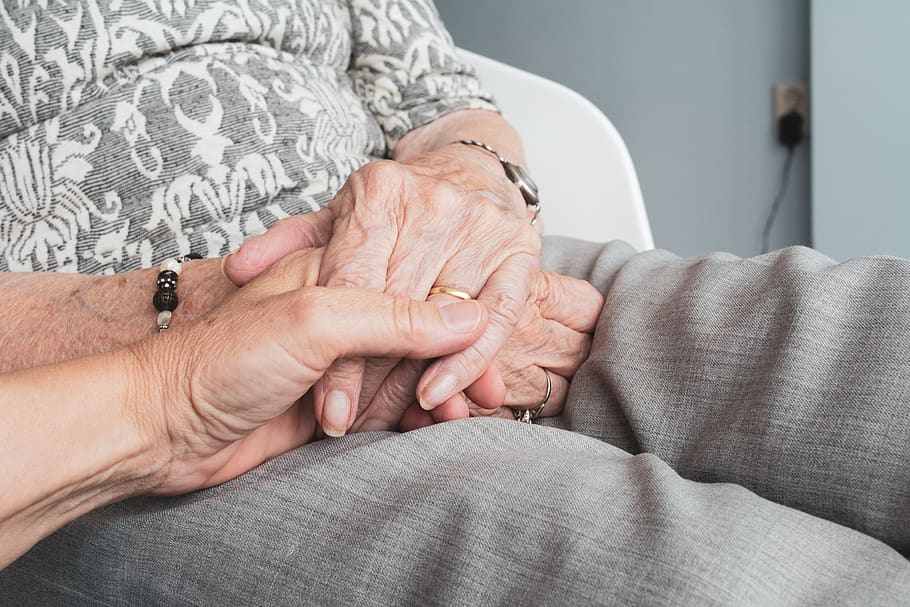 Persona tomando las manos de una anciana. | Foto: PxFuel