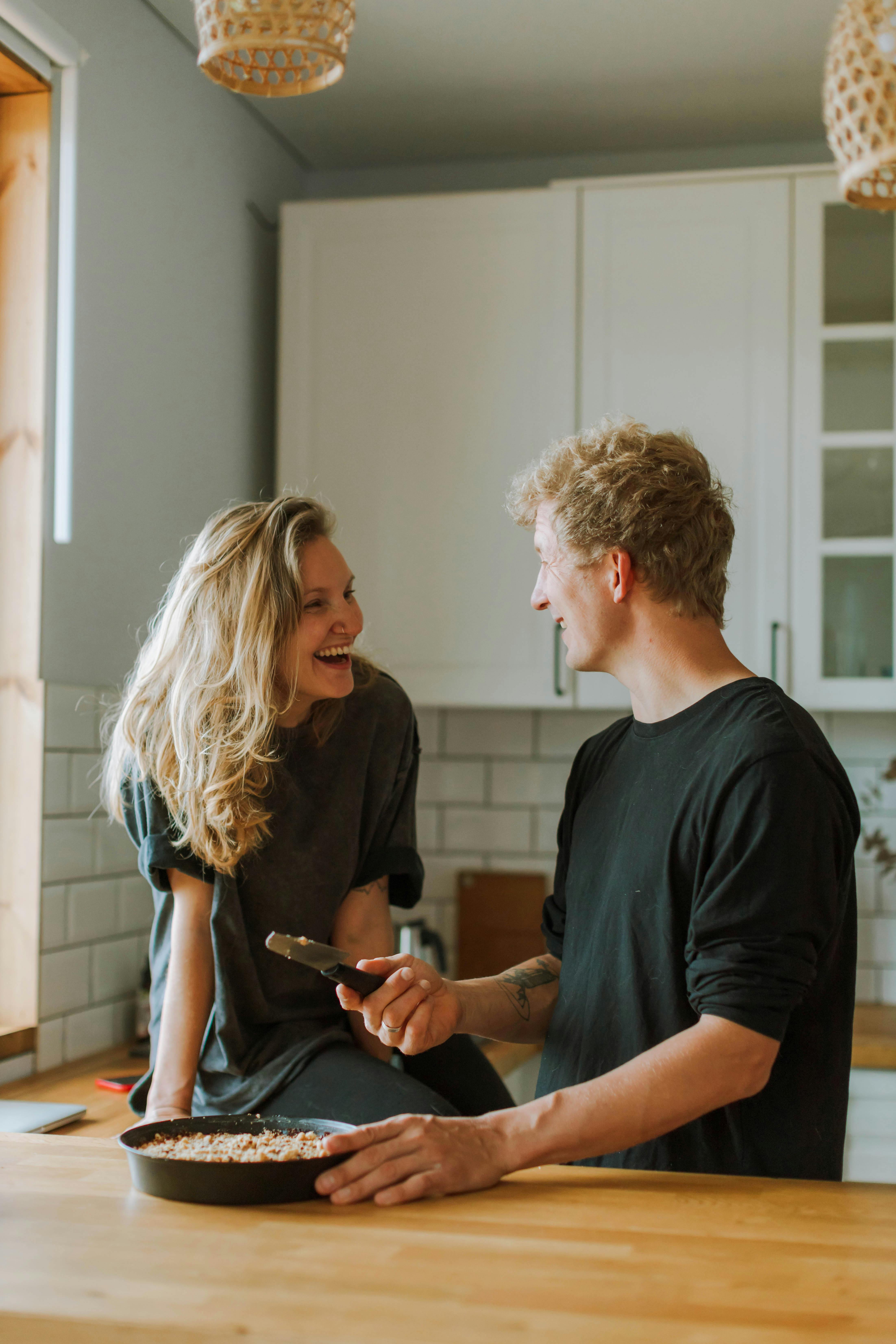 Man and woman laughing while preparing a meal in the kitchen | Source: Pexels