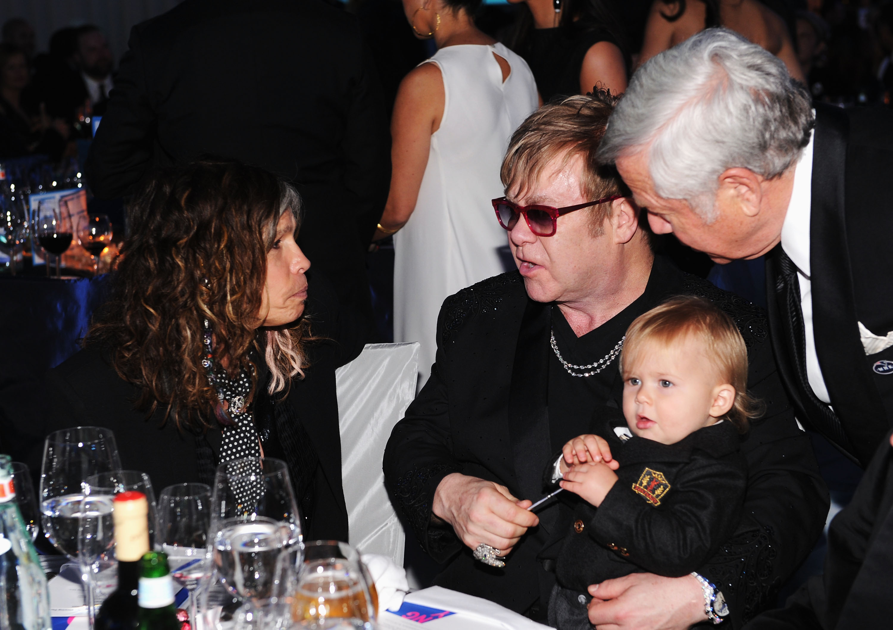 Amid the buzz of the 20th Annual Elton John AIDS Foundation Academy Awards Viewing Party on February 26, 2012, in California, Sir Elton John balanced conversation with rock legend Steven Tyler while holding toddler Zachary John Furnish-John on his lap. Dressed in a tiny dark suit, Zachary looked wide-eyed at the lively scene unfolding around him.