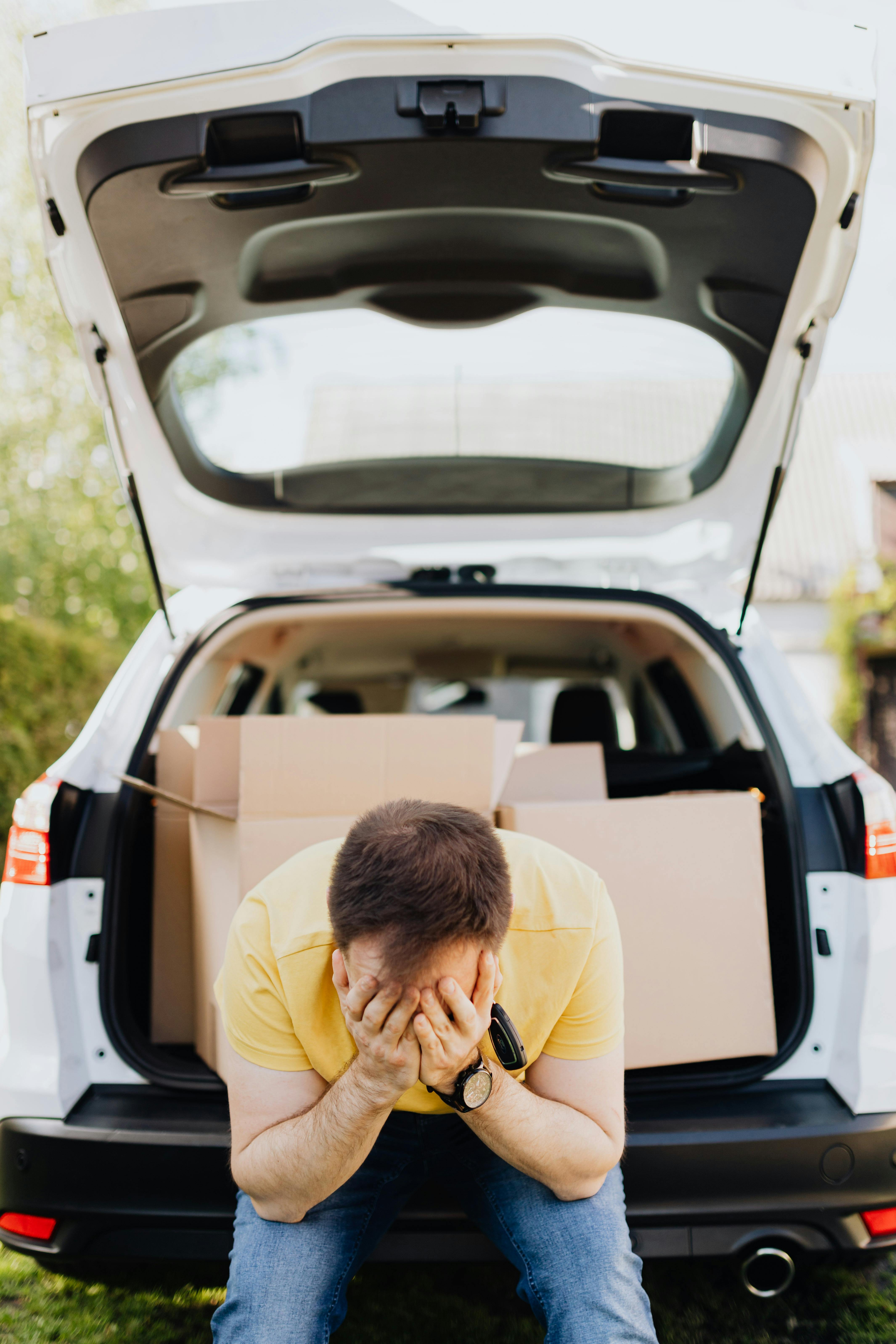 An upset man with cardboard boxes in his trunk | Source: Pexels