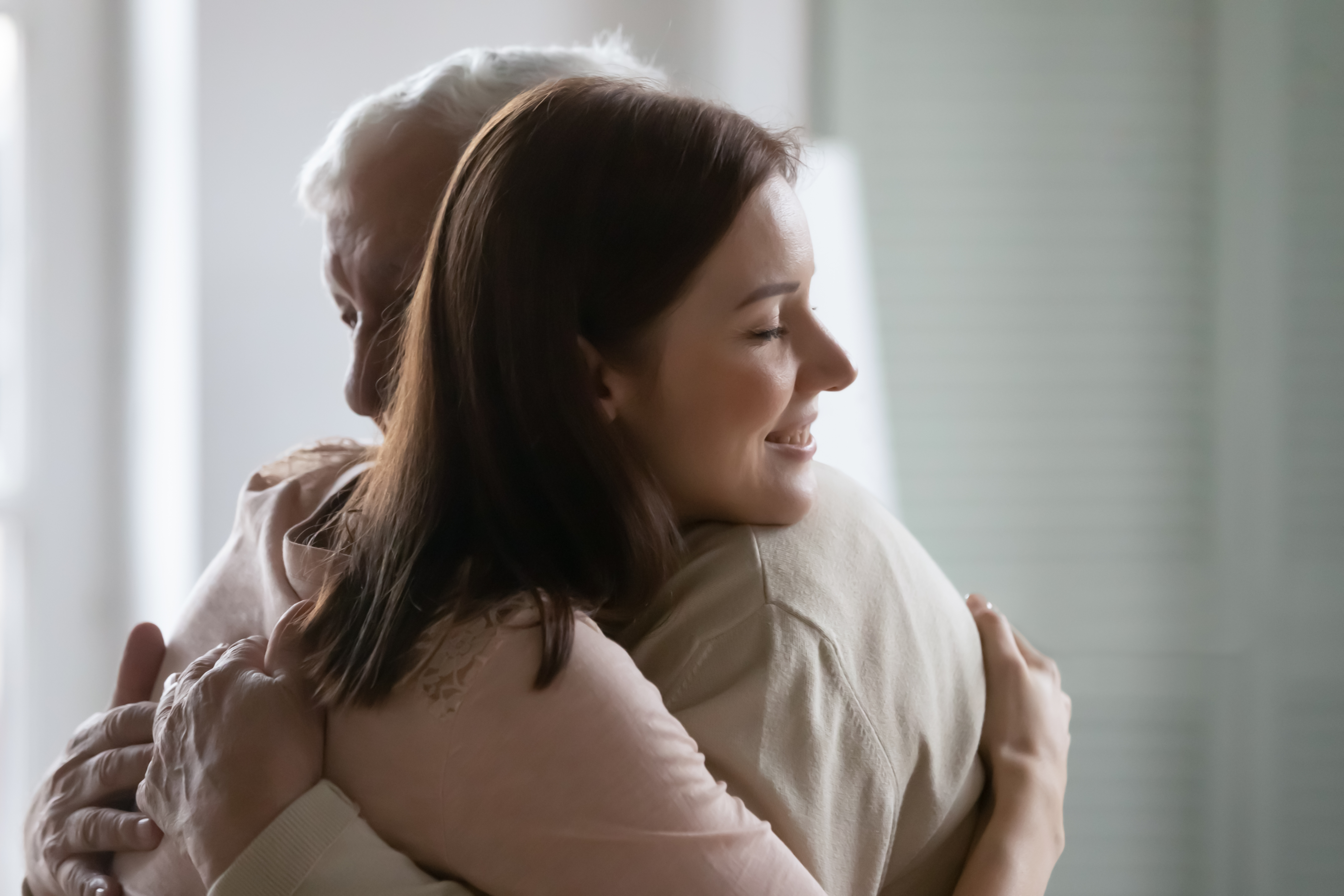 Close up smiling young beautiful woman hugging older man | Source: Shutterstock.com