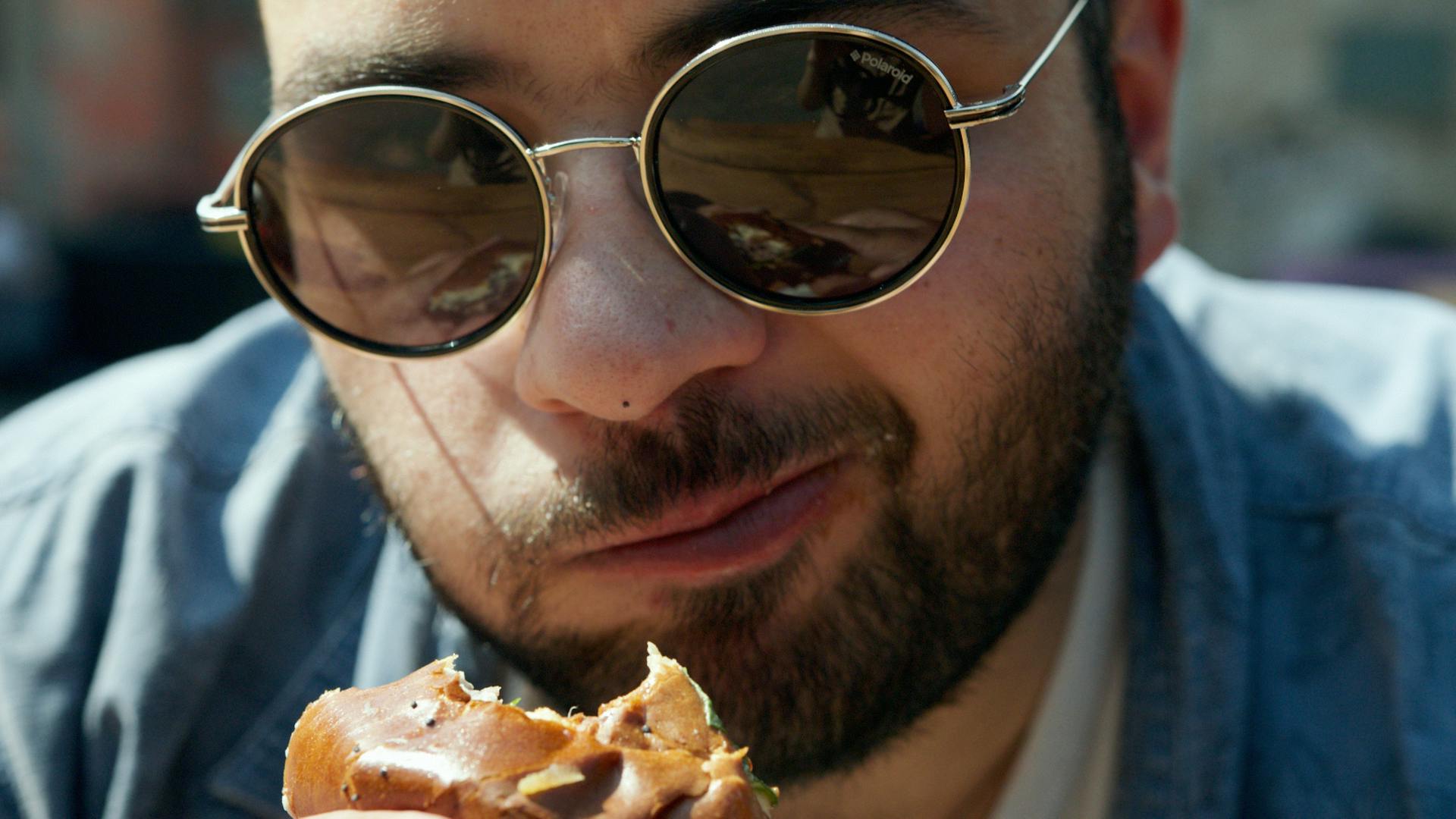 A man in black framed eyeglasses eating pizza | Source: Pexels