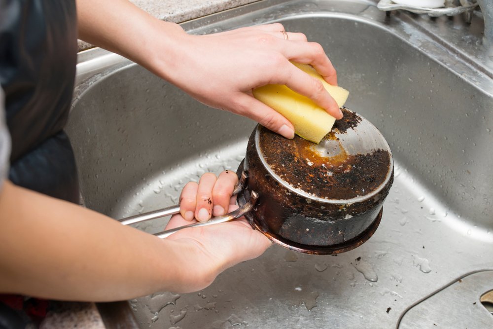 A photo of someone trying to wash a burnt pot | Photo: Shutterstock