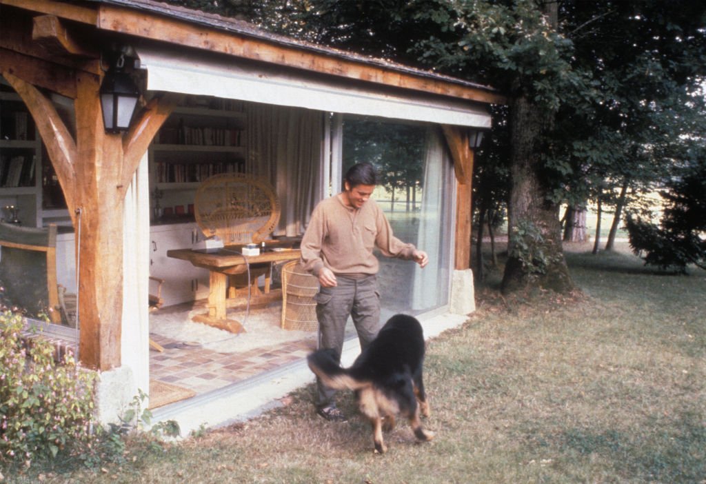 Alain Delon joue avec son chien dans sa maison de Douchy en juin 1983, France | photo : Getty Images