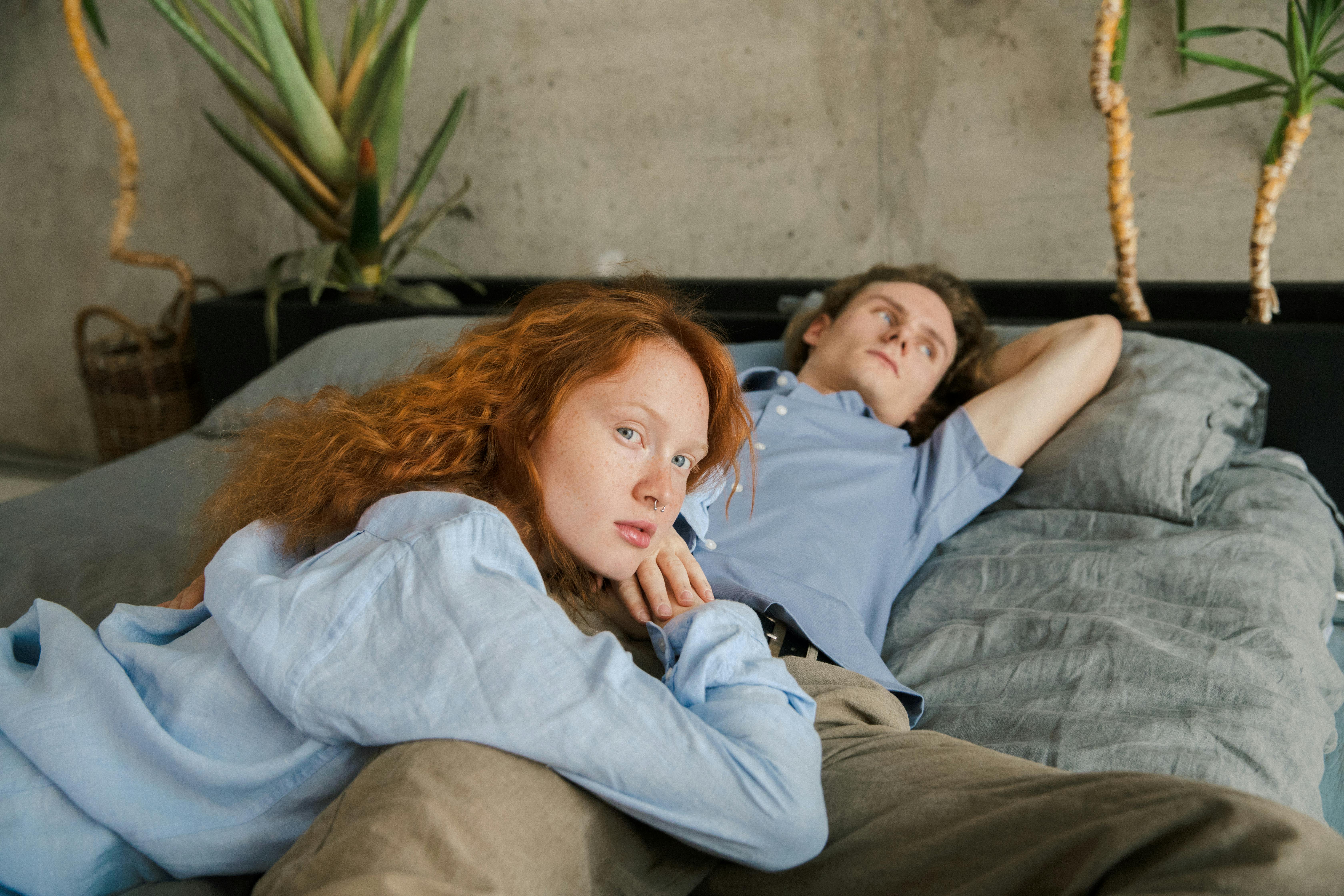 A woman looks at the camera while her man lies back contemplating something | Source: Pexels