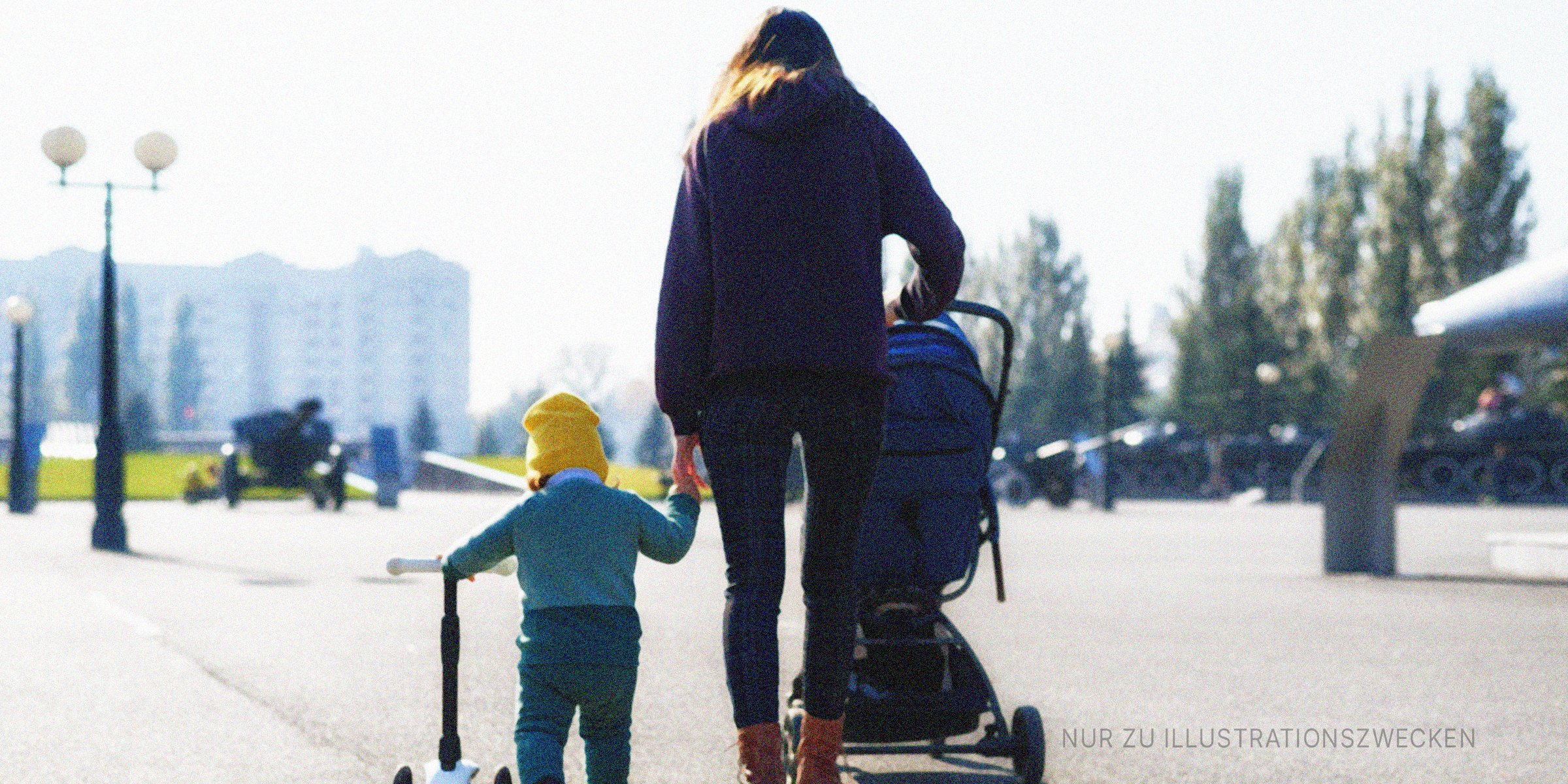 Frau geht mit ihrem Kind spazieren und schiebt einen Kinderwagen. | Quelle: Shutterstock