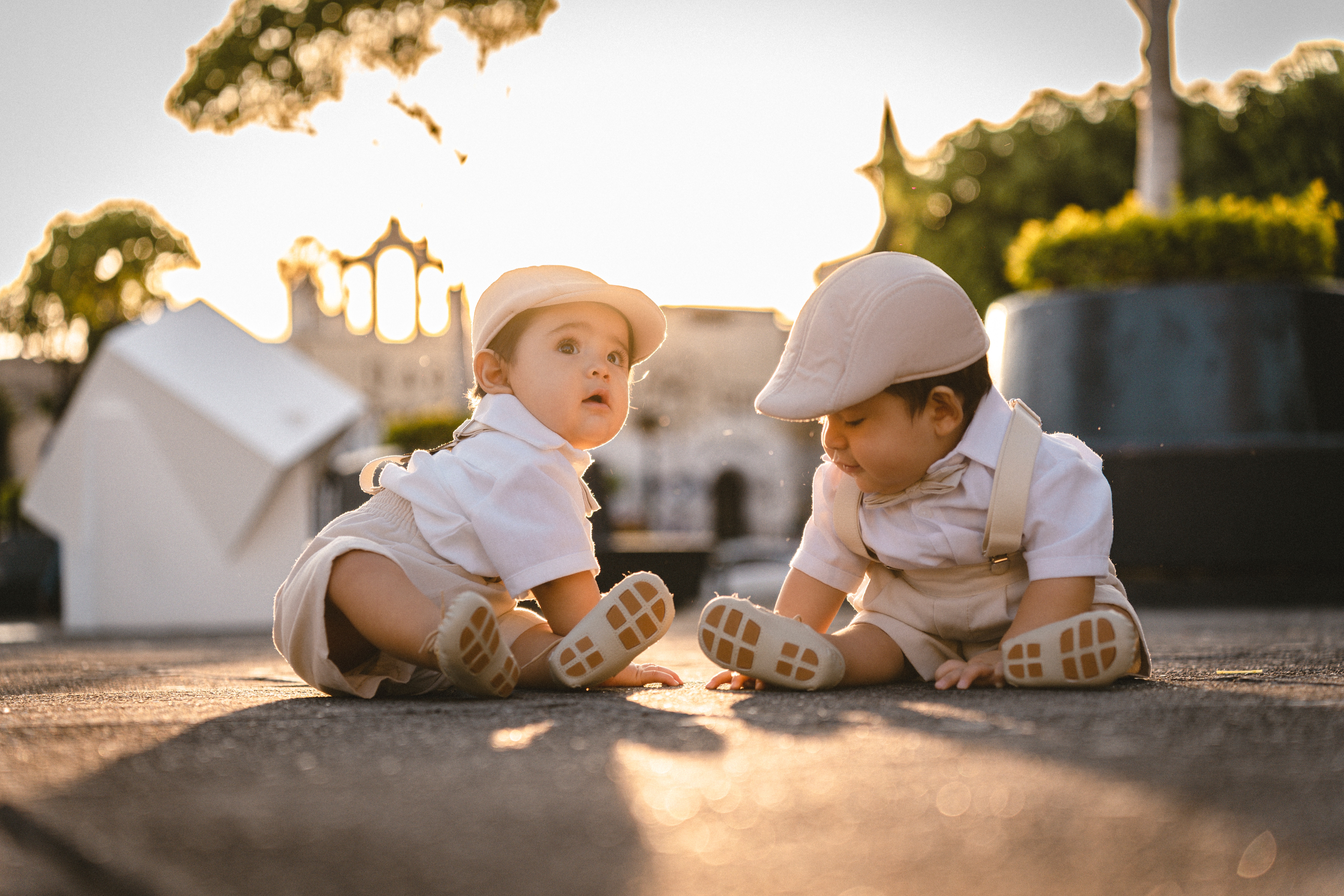 A pair of twins dressed identically and sitting on the ground | Source: Pexels