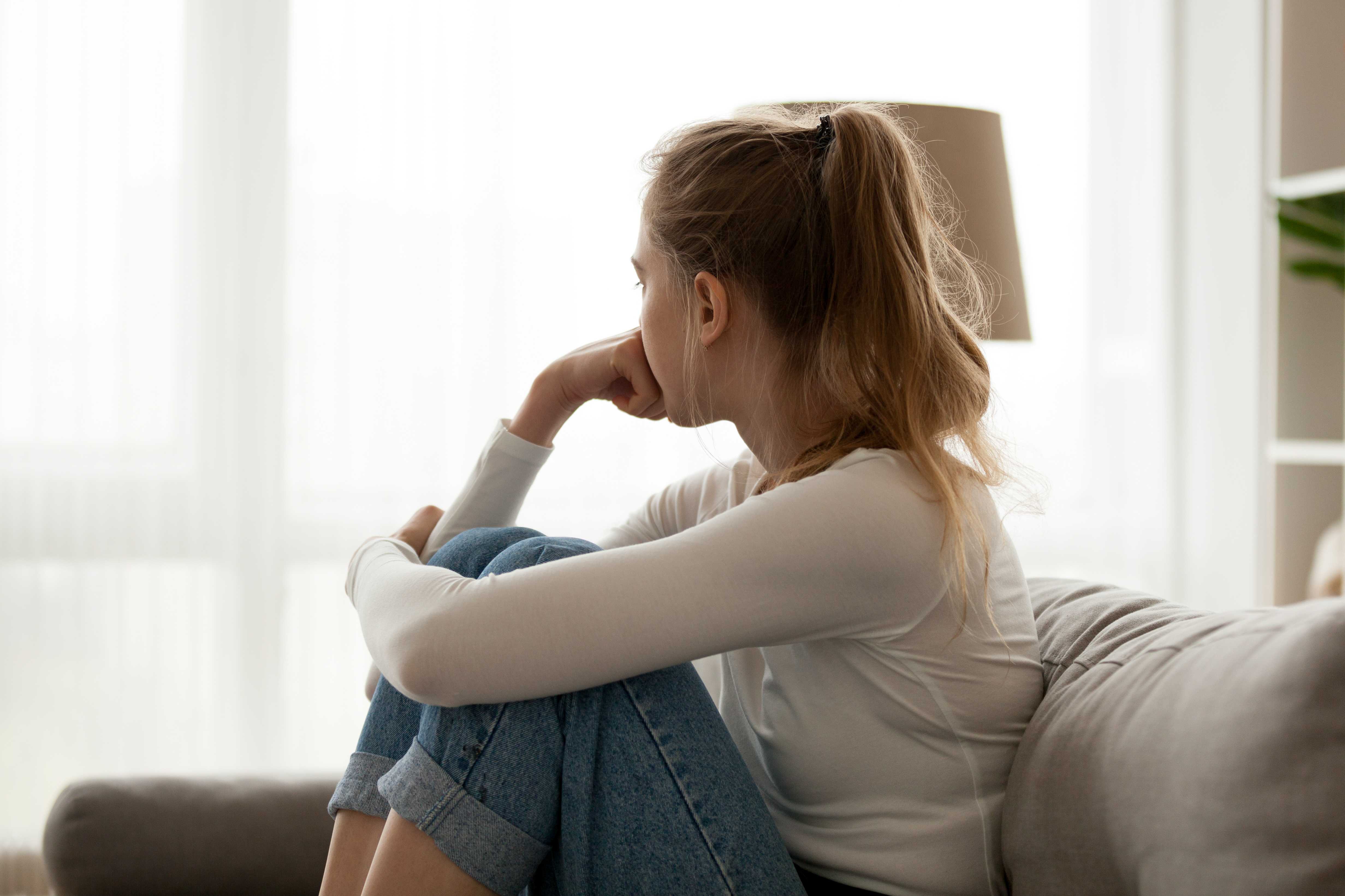 Sad woman is sitting on the sofa | Source: Shutterstock.com