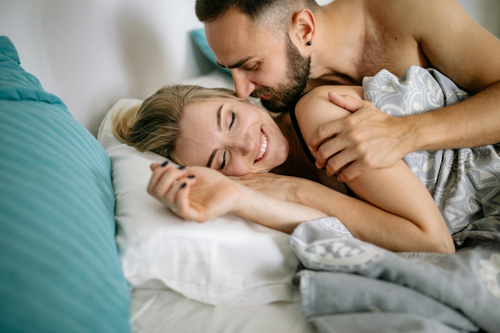 A happy couple cuddling in bed | Source: Pexels