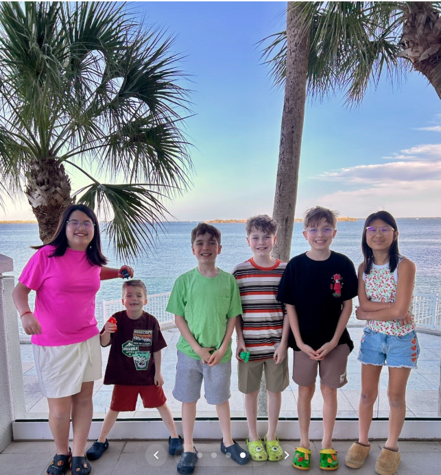 Amanda "Mandy" Karolkiewicz and Kristopher Karolkiewicz's six children pose together for a group photo with palm trees and the waterfront in the background during the family's spring break vacation. | Source: TikTok/mandykarolk
