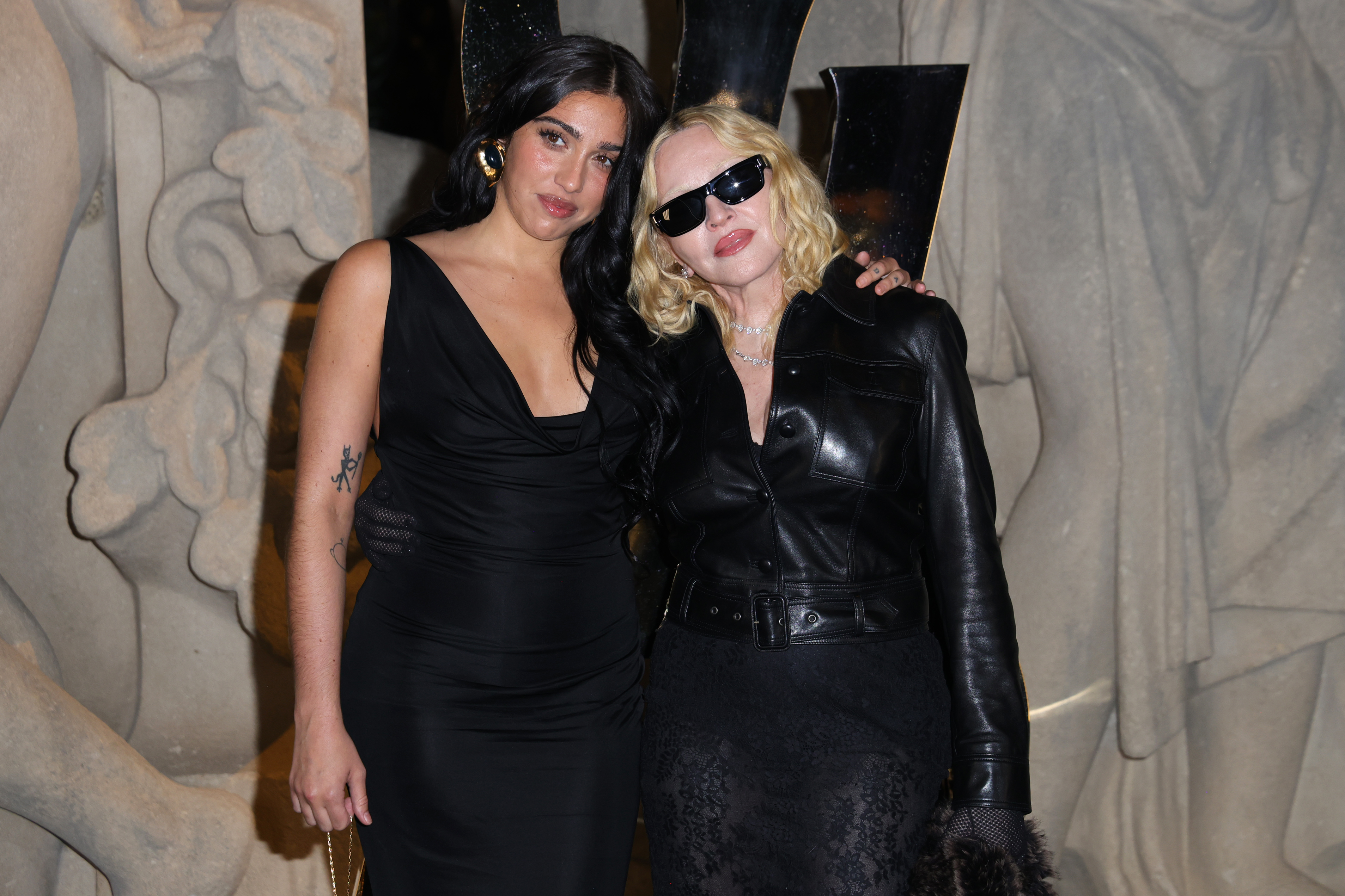 Lourdes Leon and Madonna attended the Saint Laurent Spring/Summer 2026 show at Paris Fashion Week, held at Fontaine du Trocadéro in France. Madonna wore a belted black leather button-down top with a sheer skirt and black tights, accessorized with diamond-encrusted chains. Leon opted for a black halter midi dress. She completed her look with sheer black tights.