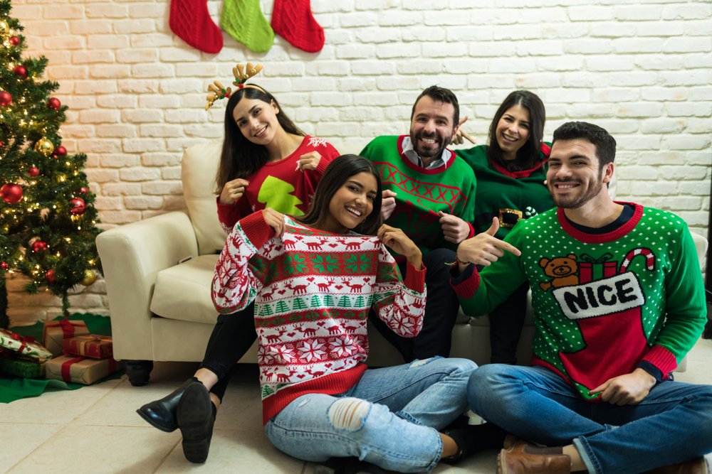Varias personas reunidas vistiendo suéteres navideños. | Foto: Shutterstock