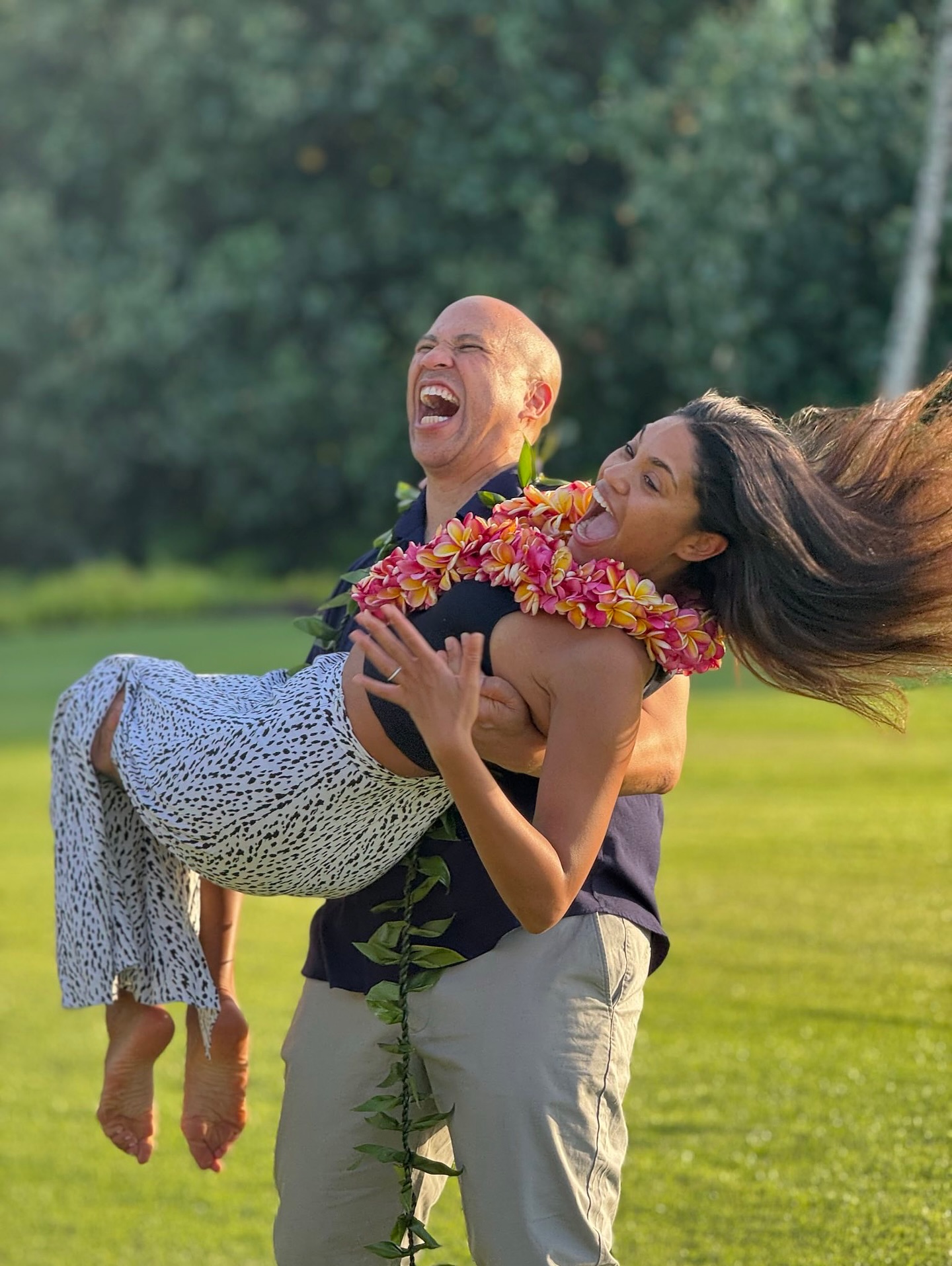 Cory Booker lifts Alexis Lewis off the ground mid-laugh, both caught in a burst of carefree energy. Their matching leis and playful expressions say everything about the fun behind the engagement. | Source: Instagram/corybooker