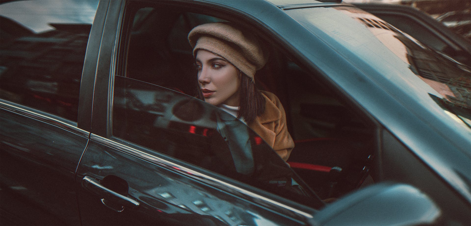 Una mujer con boina y abrigo marrón mirando por la ventana de un coche | Fuente: Pexels