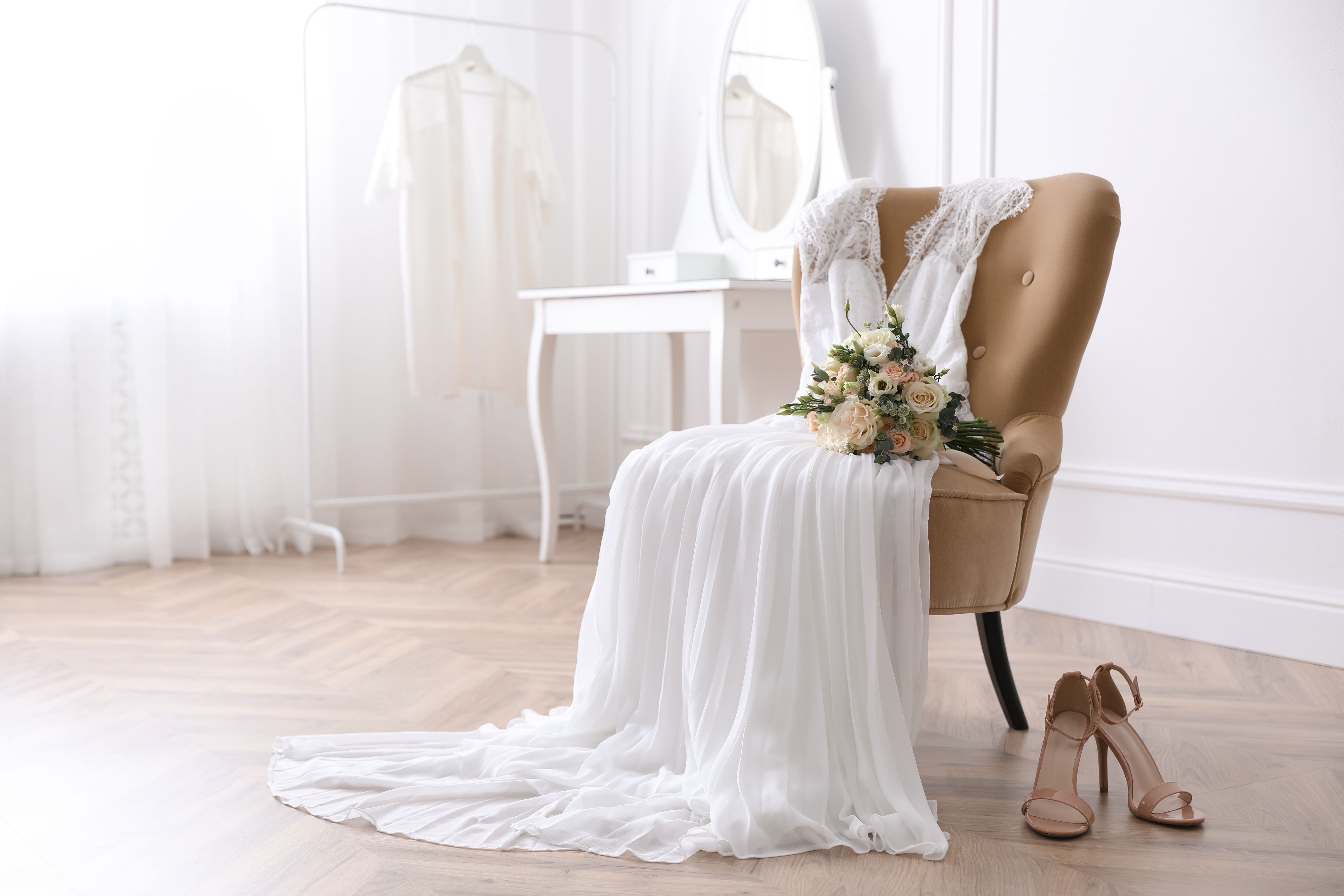 A white wedding gown on a chair with heels on the floor | Source: Shutterstock