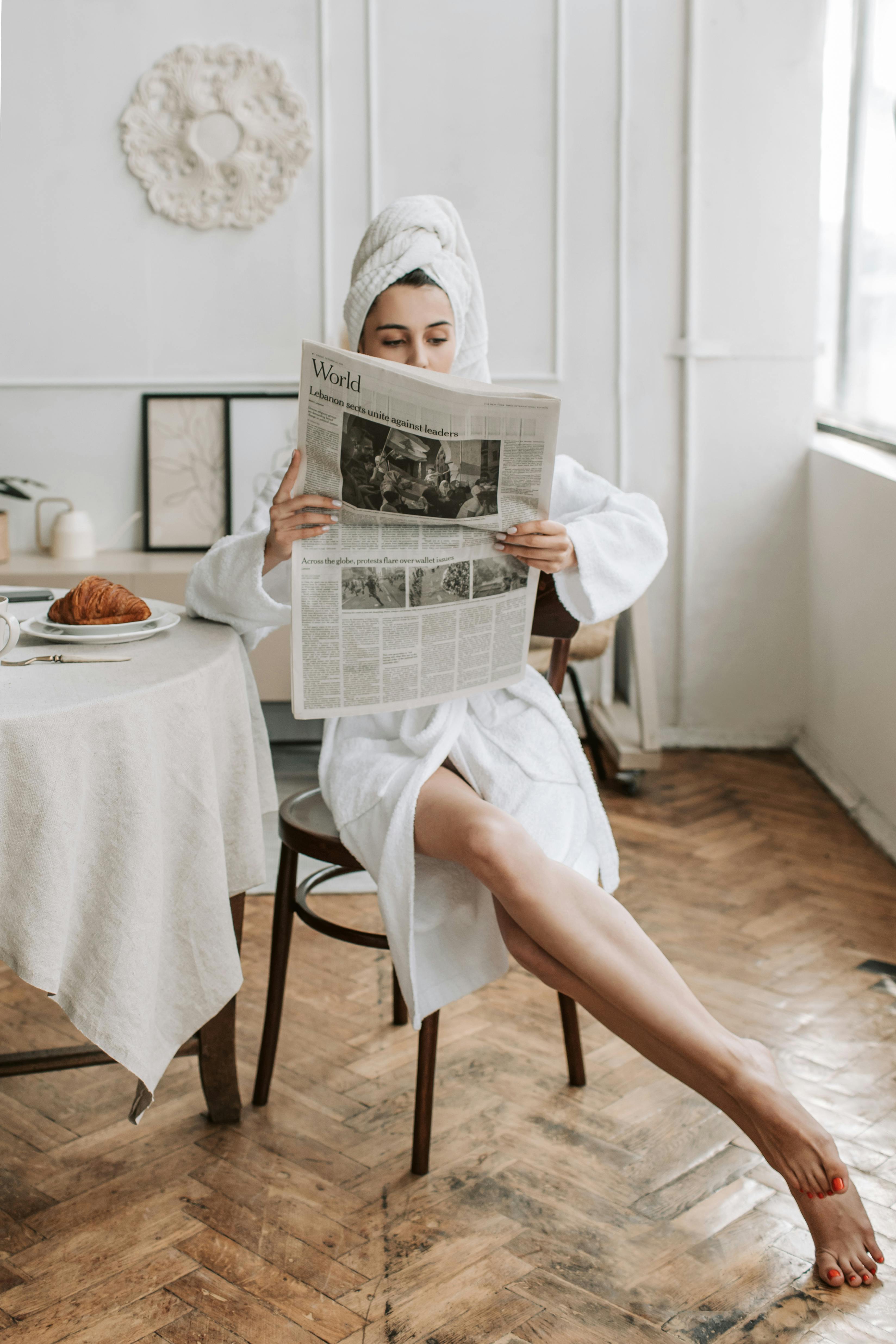 A woman reading a newspaper after showering | Source: Pexels