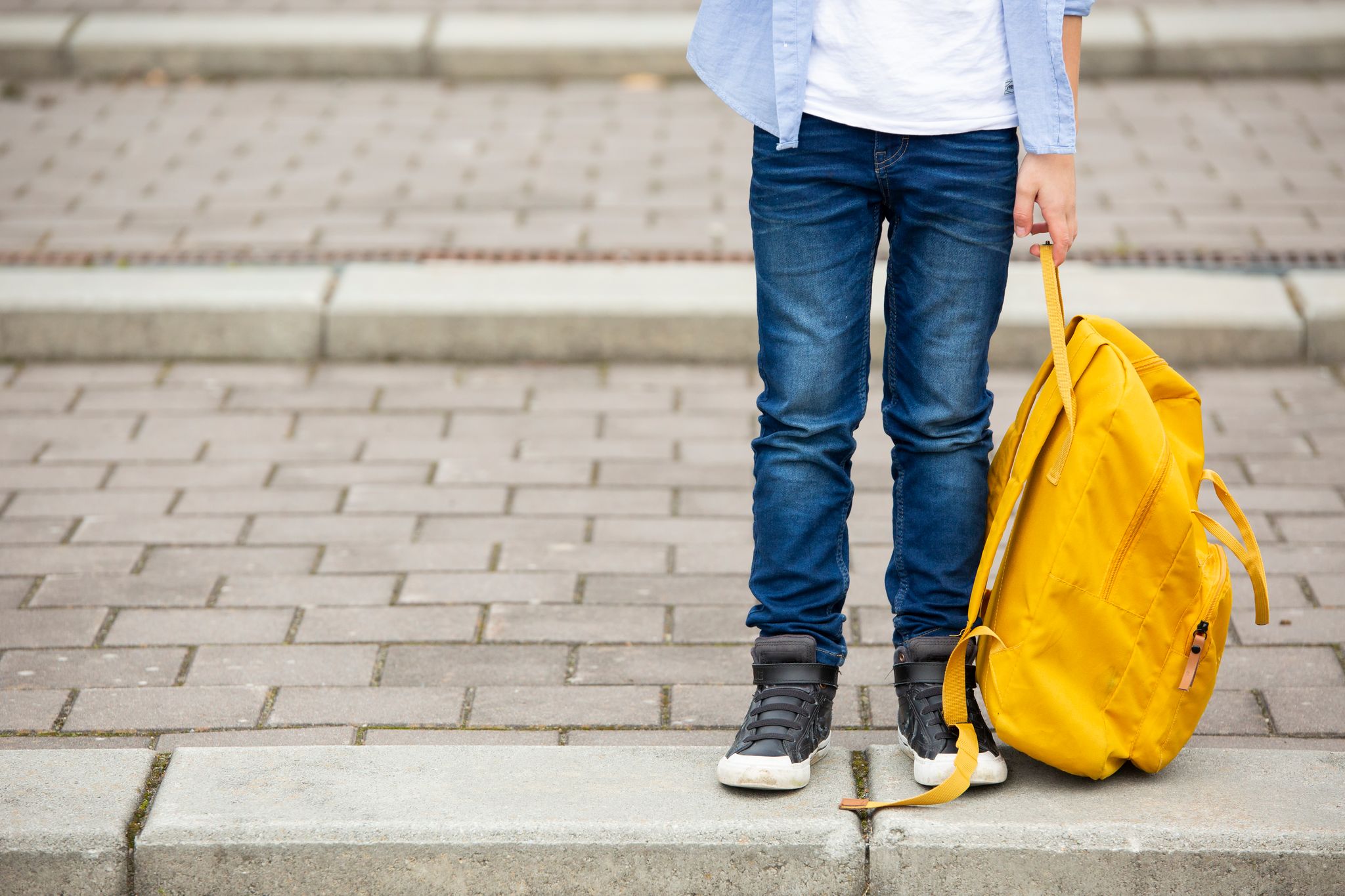 A person with a yellow bag, about to cross the street. | Source: Getty Images