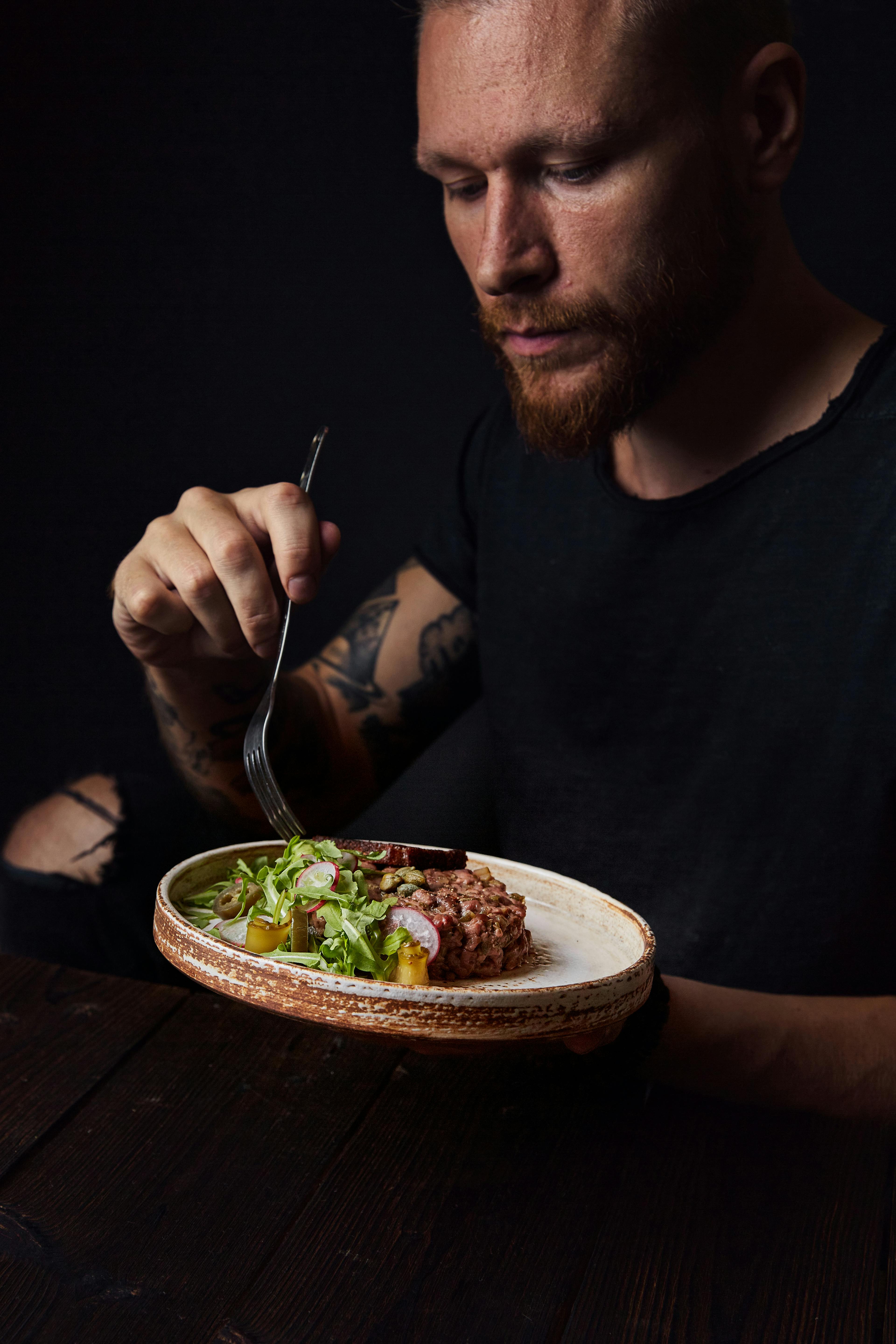 A man eating against a dark backdrop