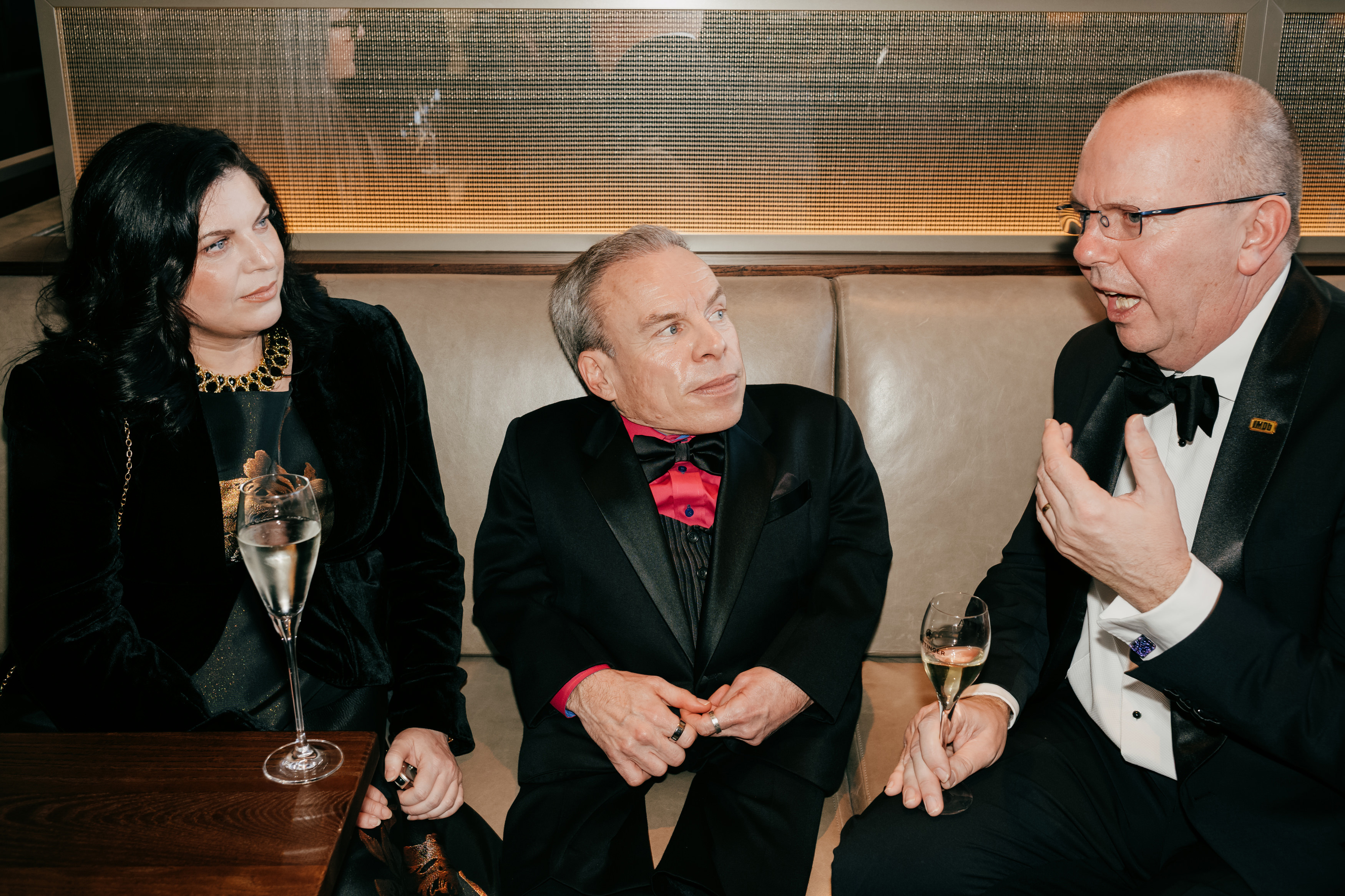 Guest (L), Warwick Davis (C) and Col Needham (R) attend the EE BAFTA Film Awards 2026 Champagne Reception at The Royal Festival Hall on  22 February 2026 in London, England. | Source: Getty Images