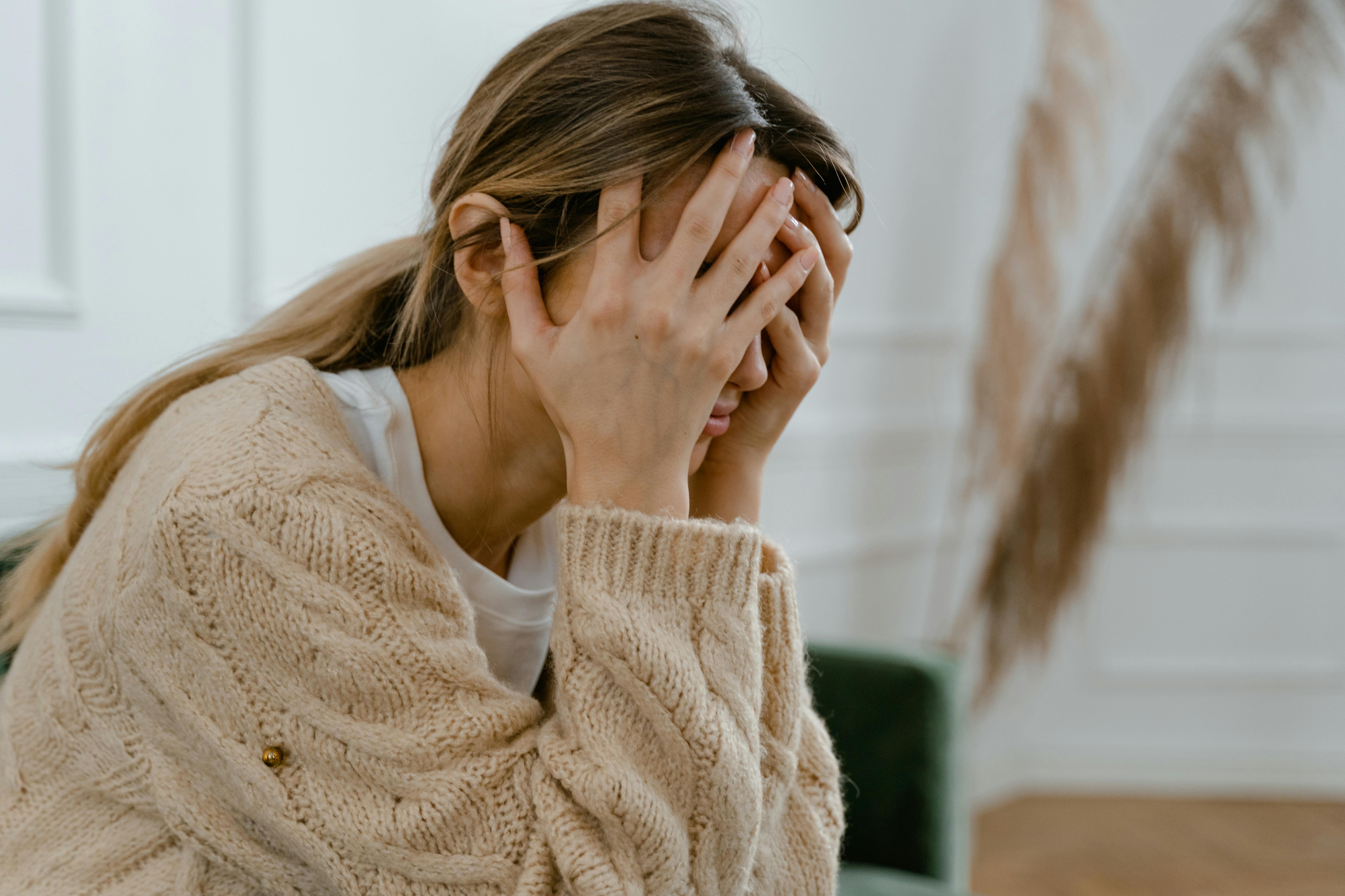 A distressed and upset woman covering her face with her hands | Source: Pexels