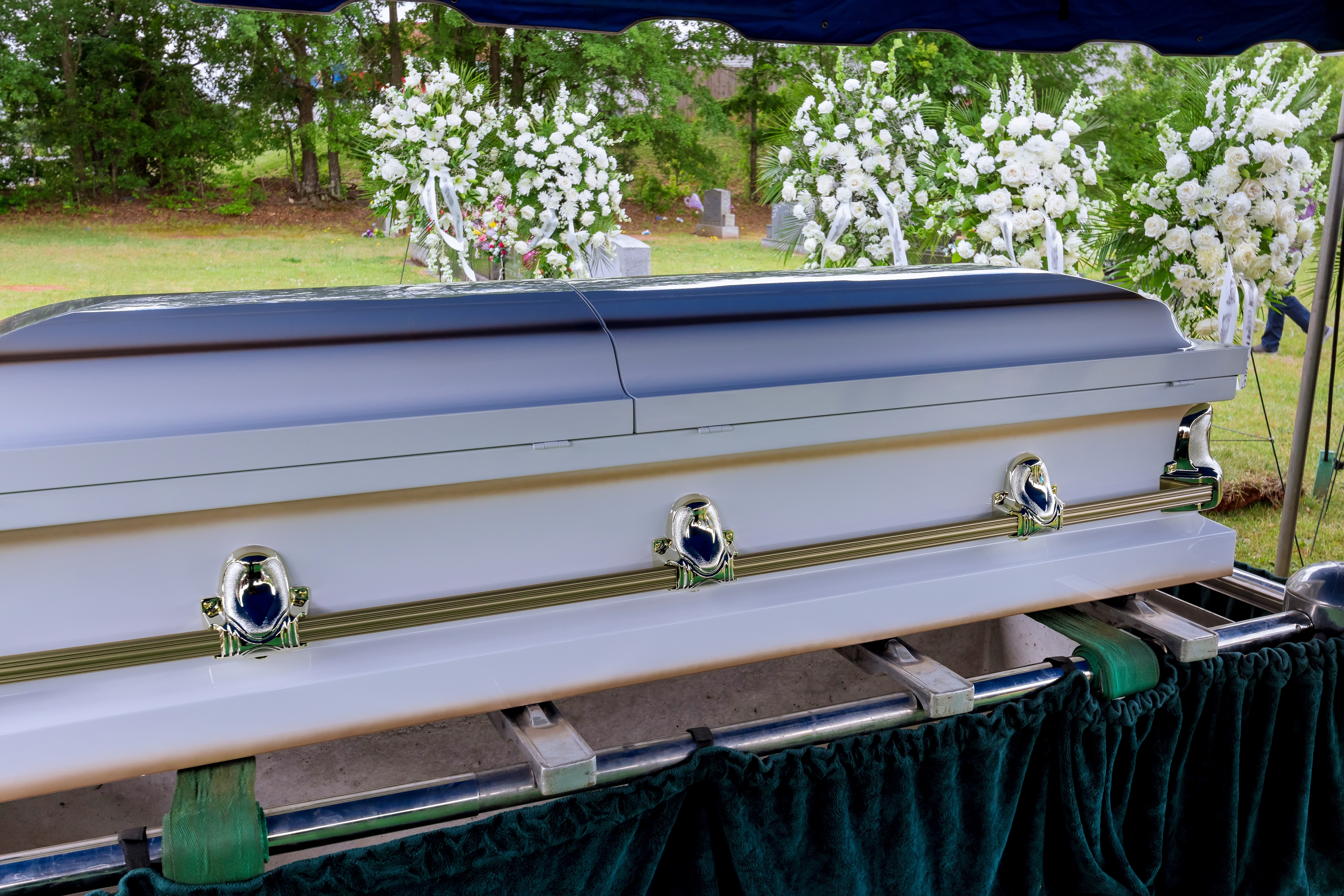 A funeral service is held in a cemetery, followed by the coffin being lowered into the grave by an automatic elevator before burial | Source: Shutterstock