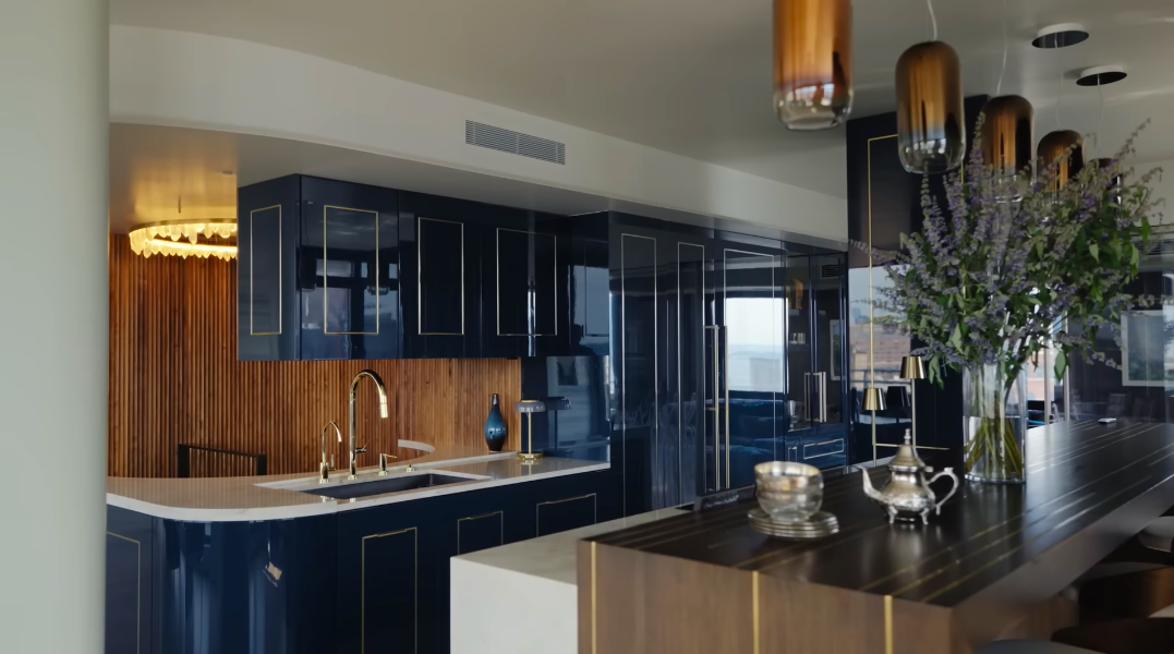 Glossy navy cabinetry, brass details and warm fluted wood give the kitchen a distinctly glamorous identity. Sherman's use of flowers and organic materials stops all that polish from becoming too slick. | Source: YouTube/Architectural Digest