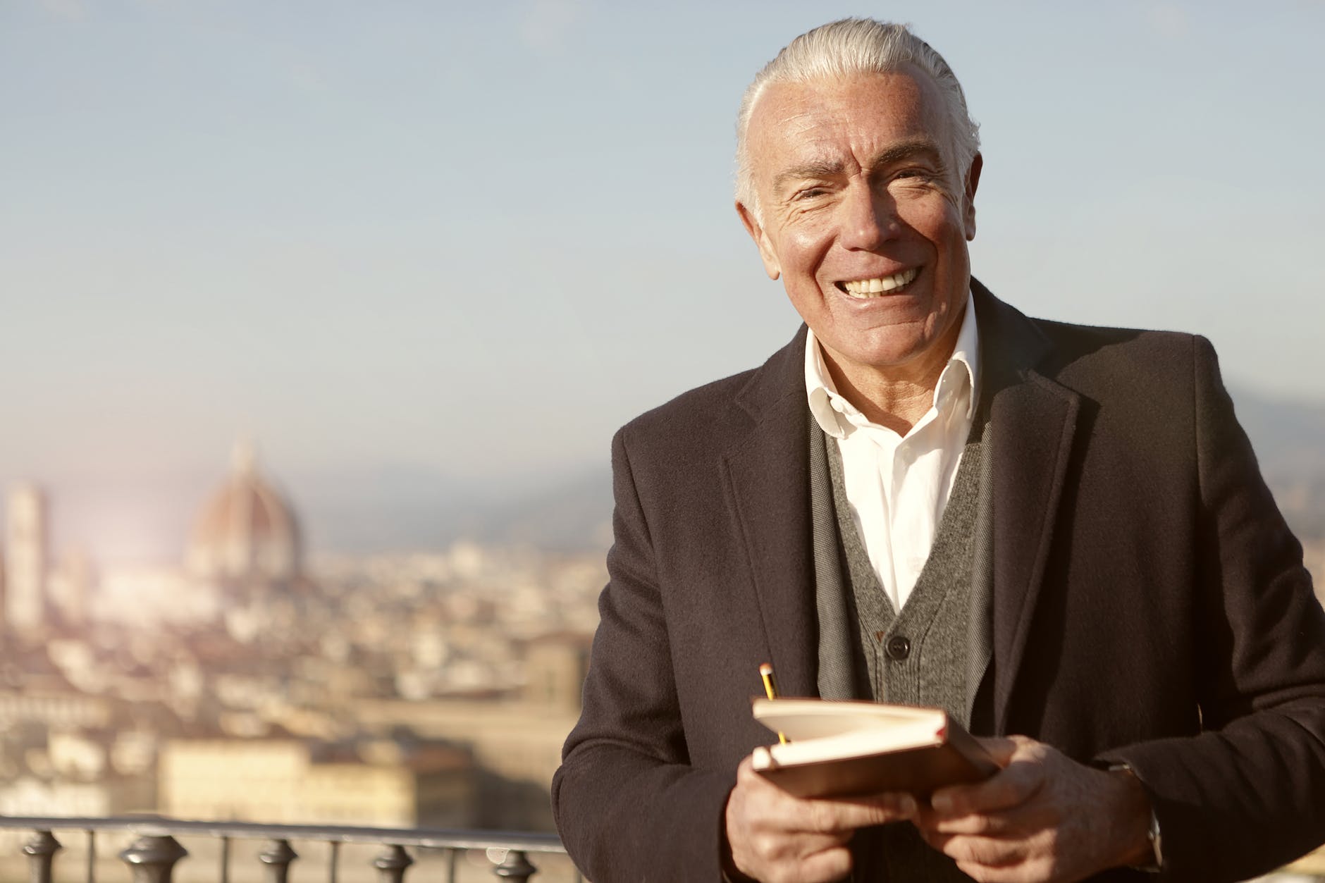 Hombre sonriendo mientras sostiene un libro. | Foto: Pexels
