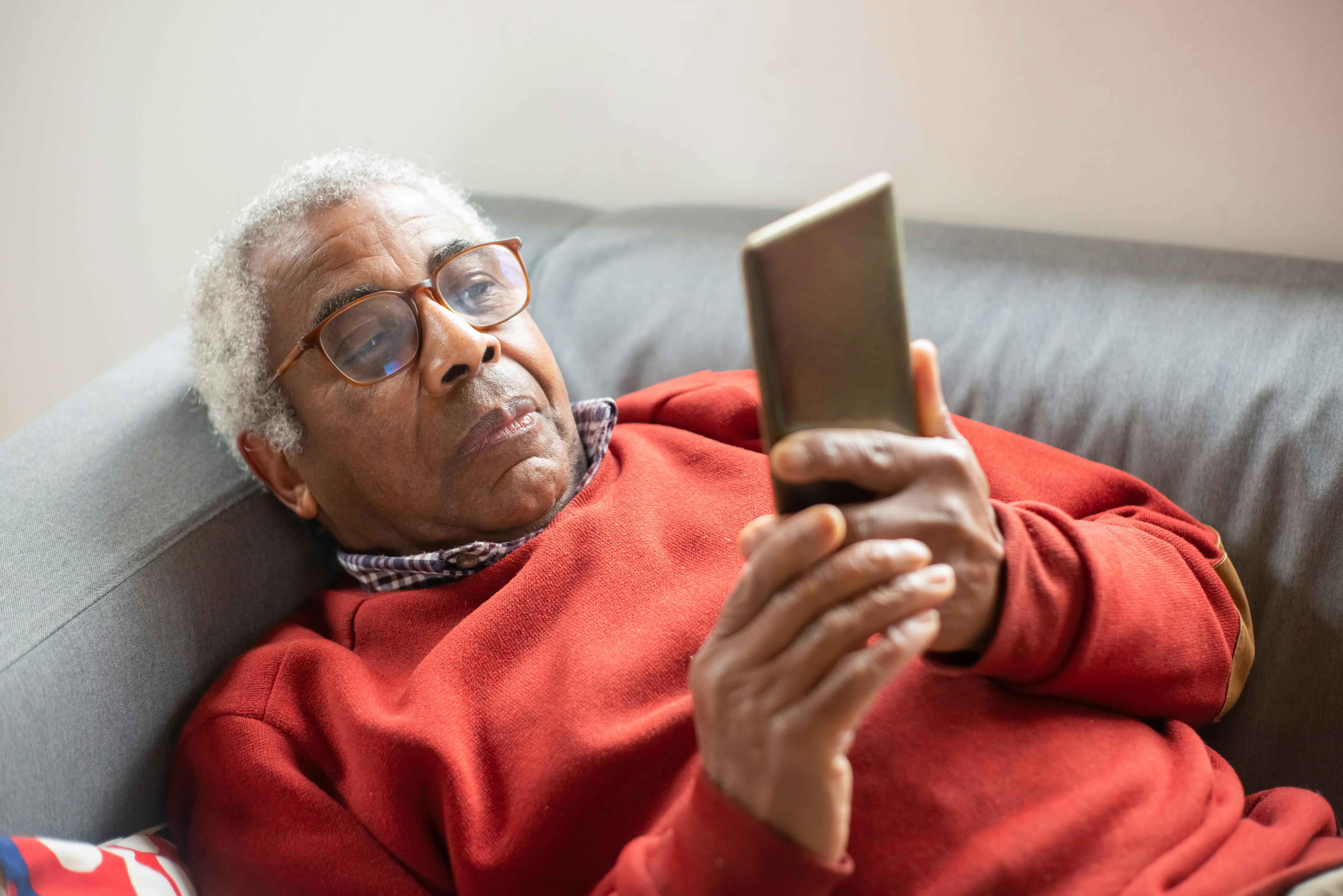 An elderly man reclines with a cell phone | Source: Pexels