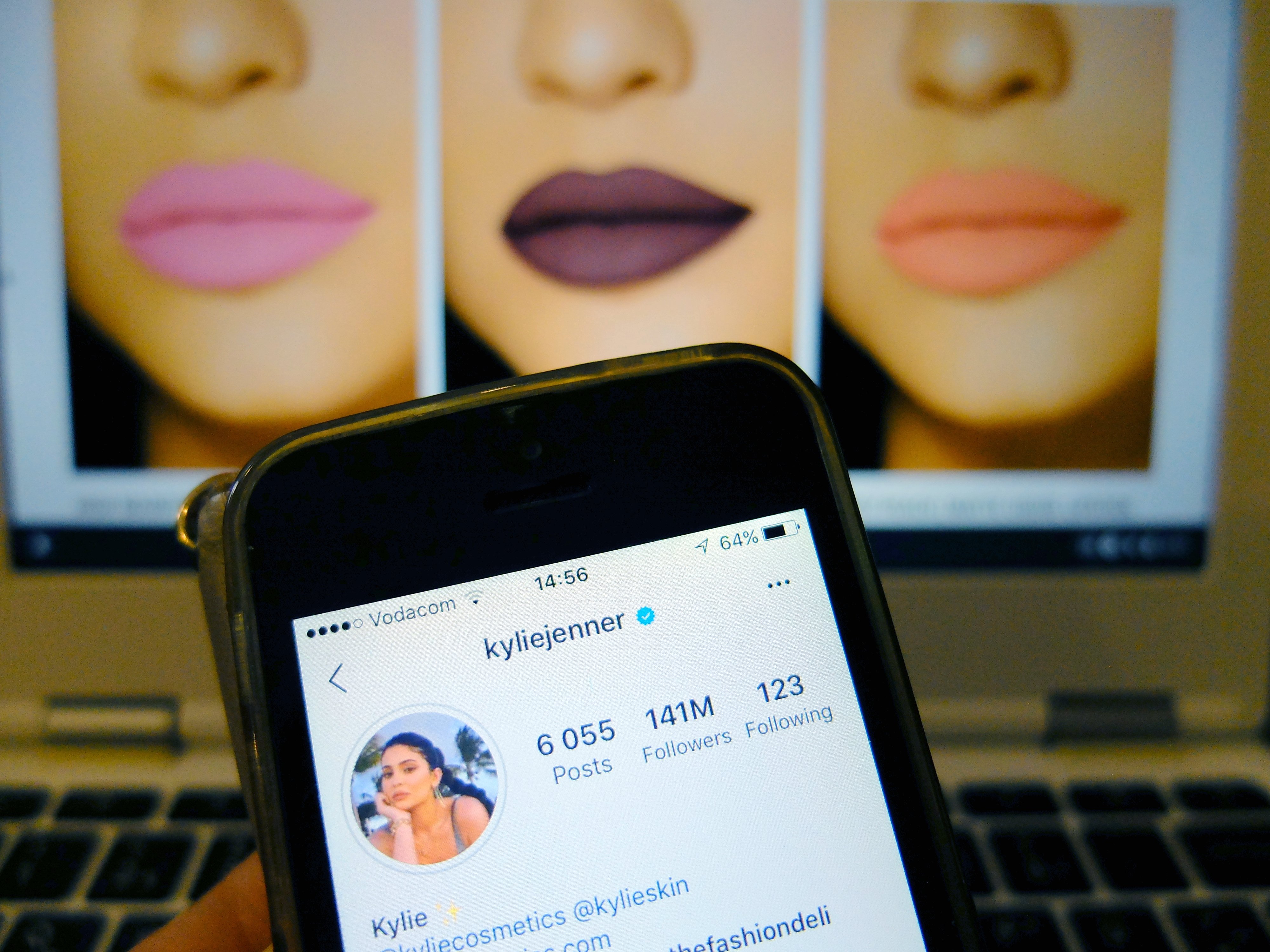 Labios rellenos y de colores en pantalla y perfil de Kylie Jenner en Instagram en dispositivo móvil. | Foto: Shutterstock