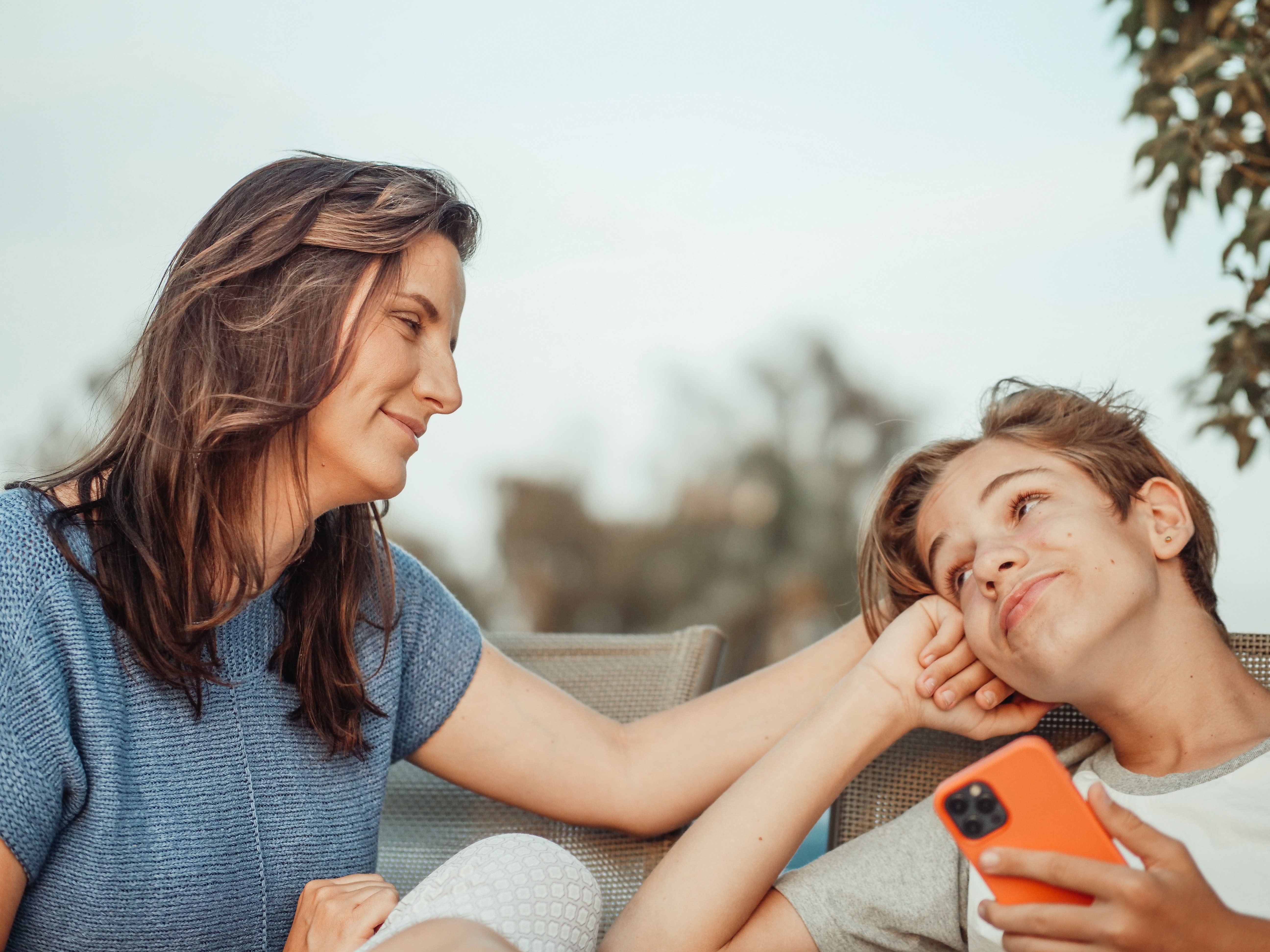 A young boy smiling while being comforted by his mother | Source: Pexels