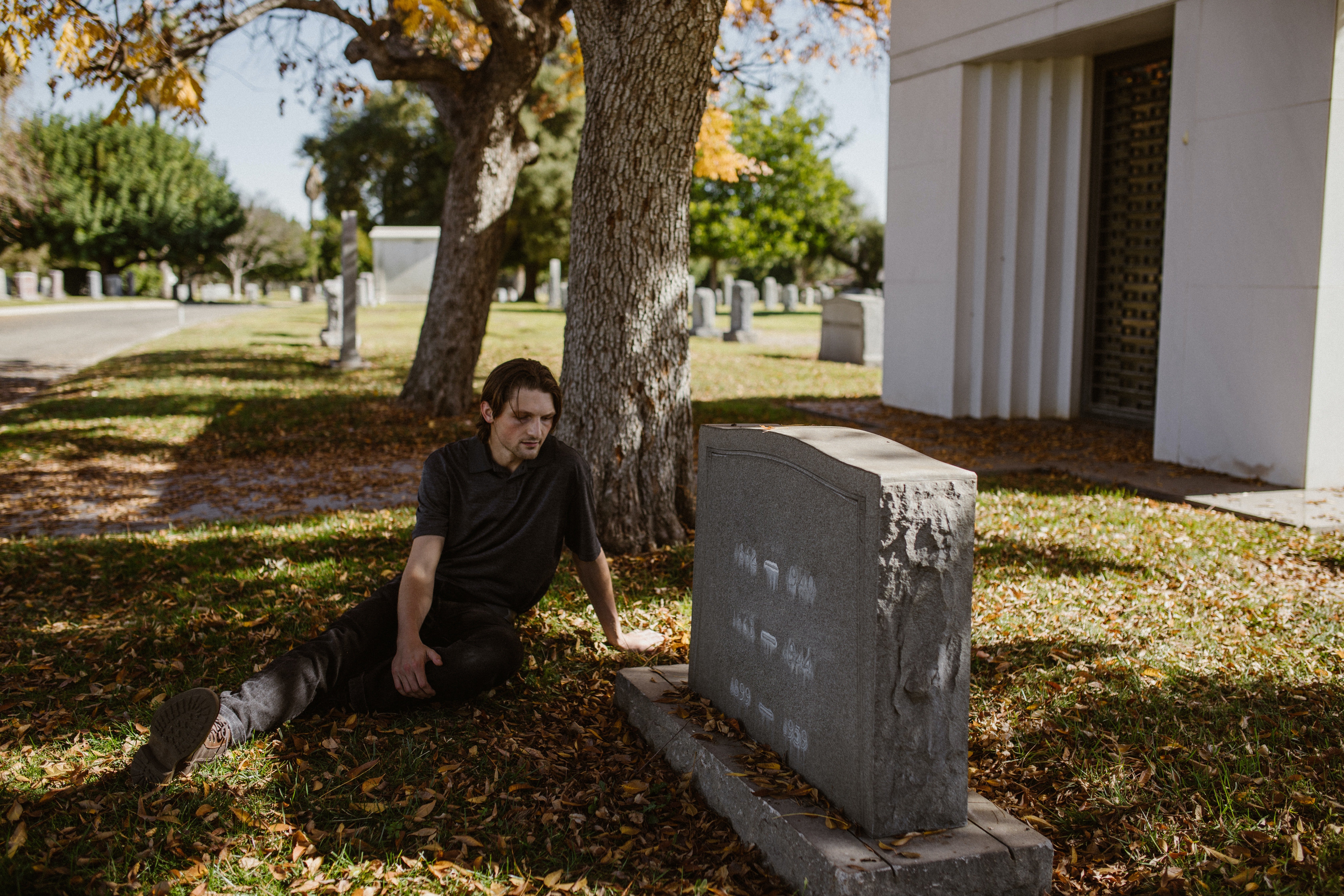 Un hombre sentado junto a una tumba en un cementerio. | Foto: Pexels
