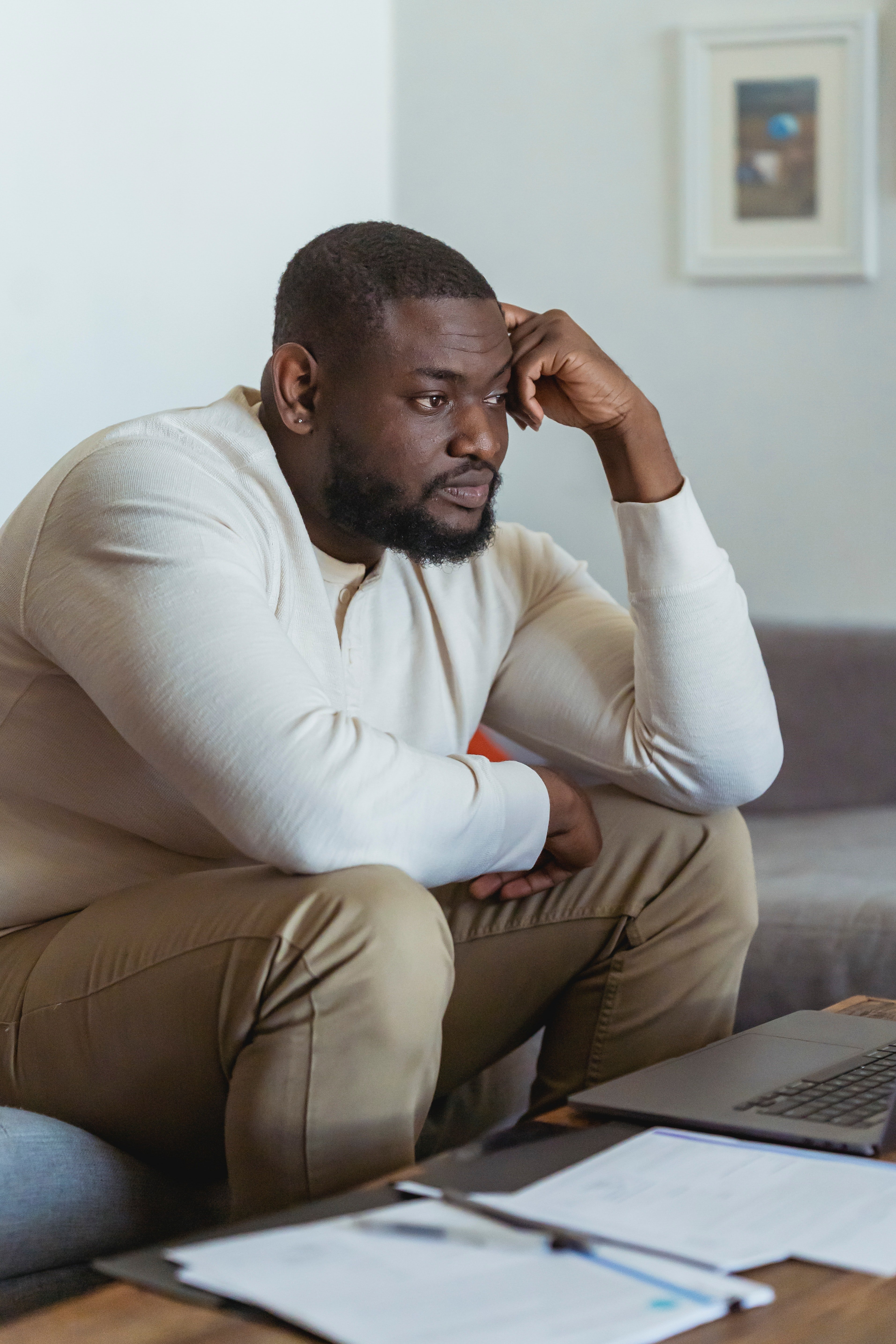 Frustrated black man sitting near laptop and thinking | Photo: Pexels