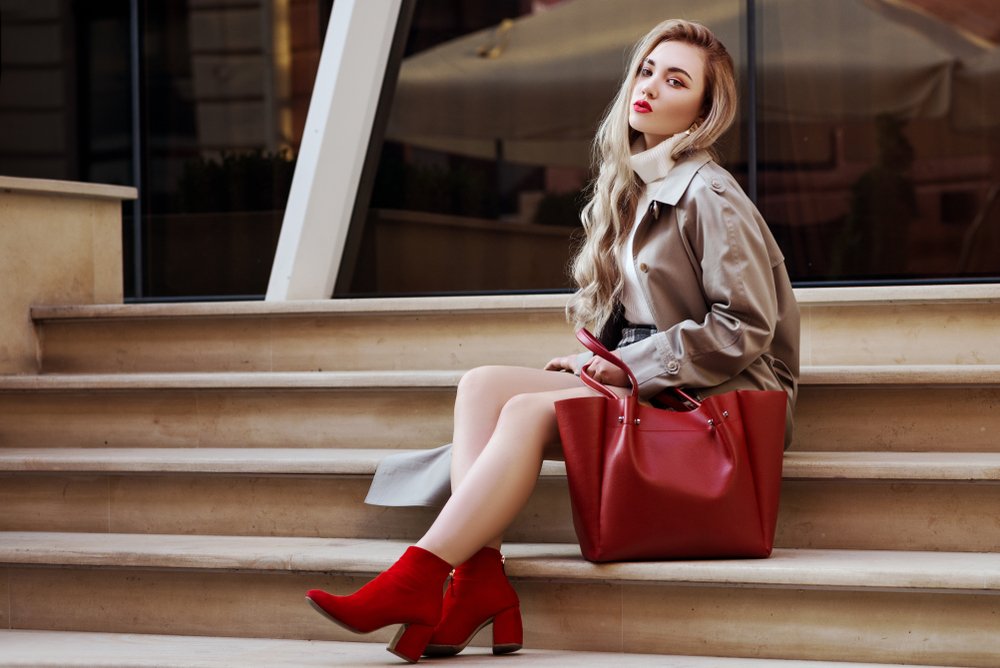 Mujer sentada en un escalón usando botines rojos y bolso rojo. | Foto: Shutterstock