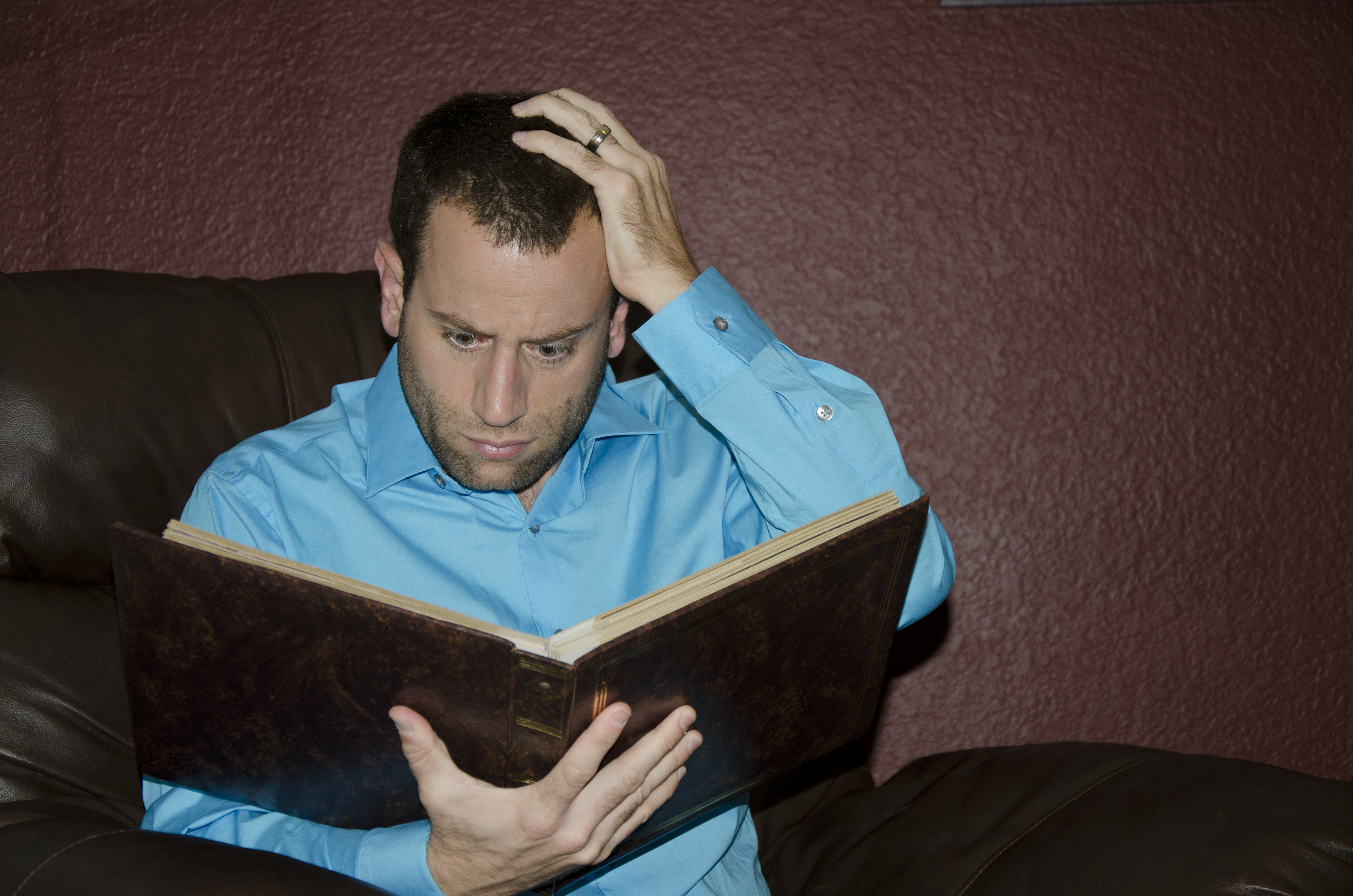 A shocked man looking at an old photo album | Source: Shutterstock
