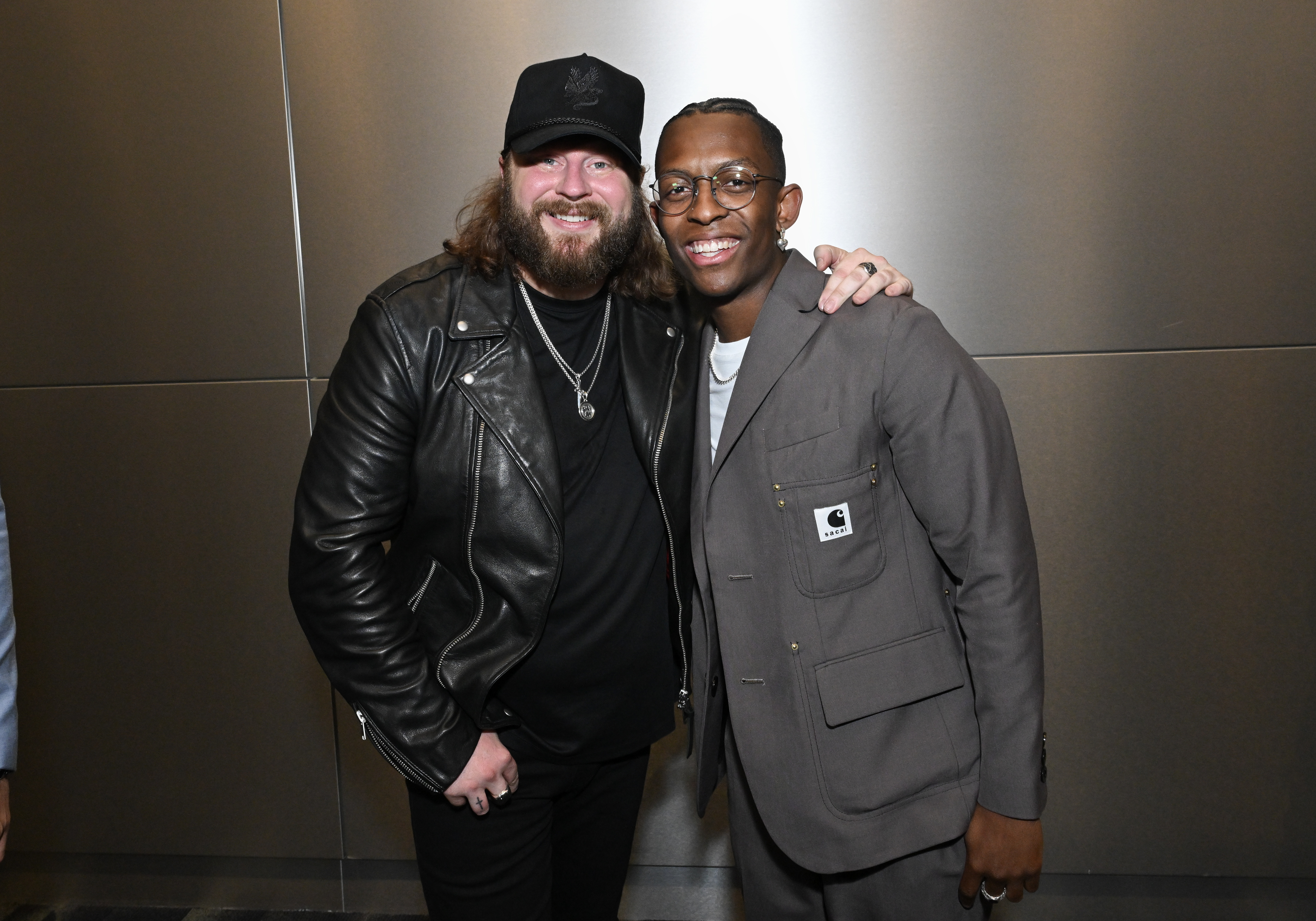 Nate Smith beams beside Breland backstage, wrapping an arm around the singer as the pair share a relaxed moment away from the awards-show spotlight.