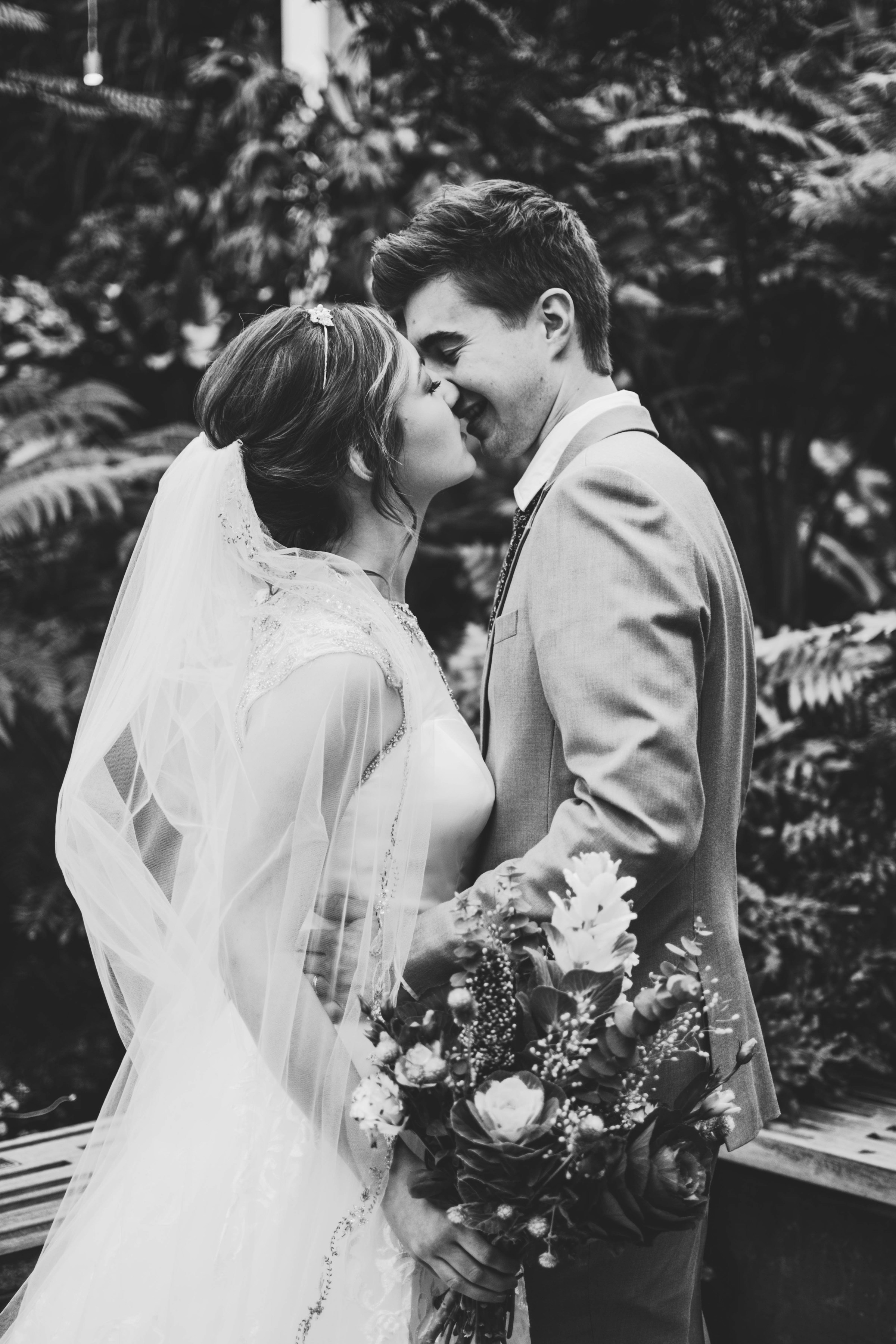 A grayscale shot of a bride and groom kissing each other | Source: Unsplash