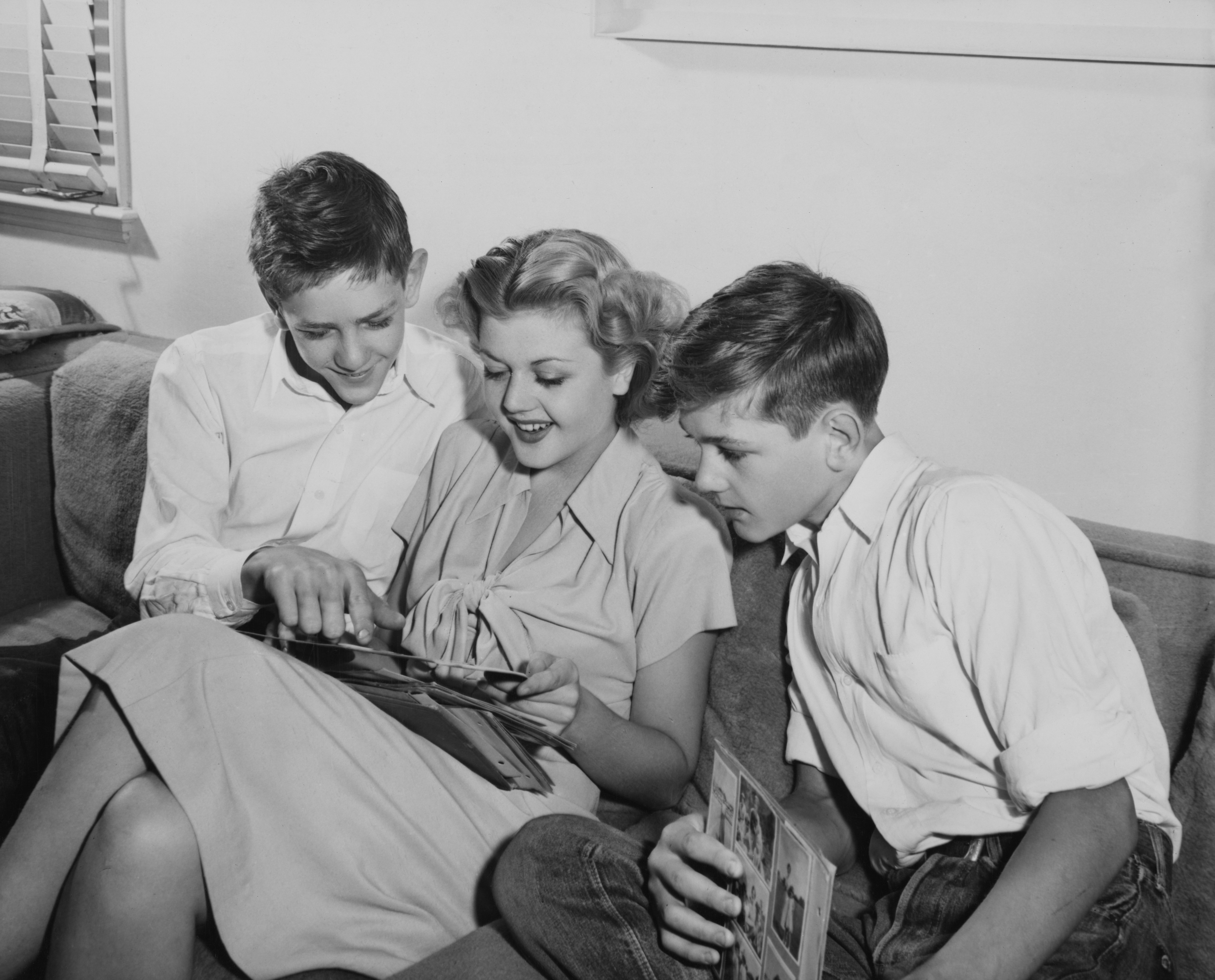 British-born Irish-American television producer and screenwriter Bruce Lansbury, with his sister Irish-British actress Angela Lansbury, and twin brother, British-born Irish-American film and television producer Edgar Lansbury, looking through a scrapbook at the family home in London, England, circa 1945. | Source: Getty Images